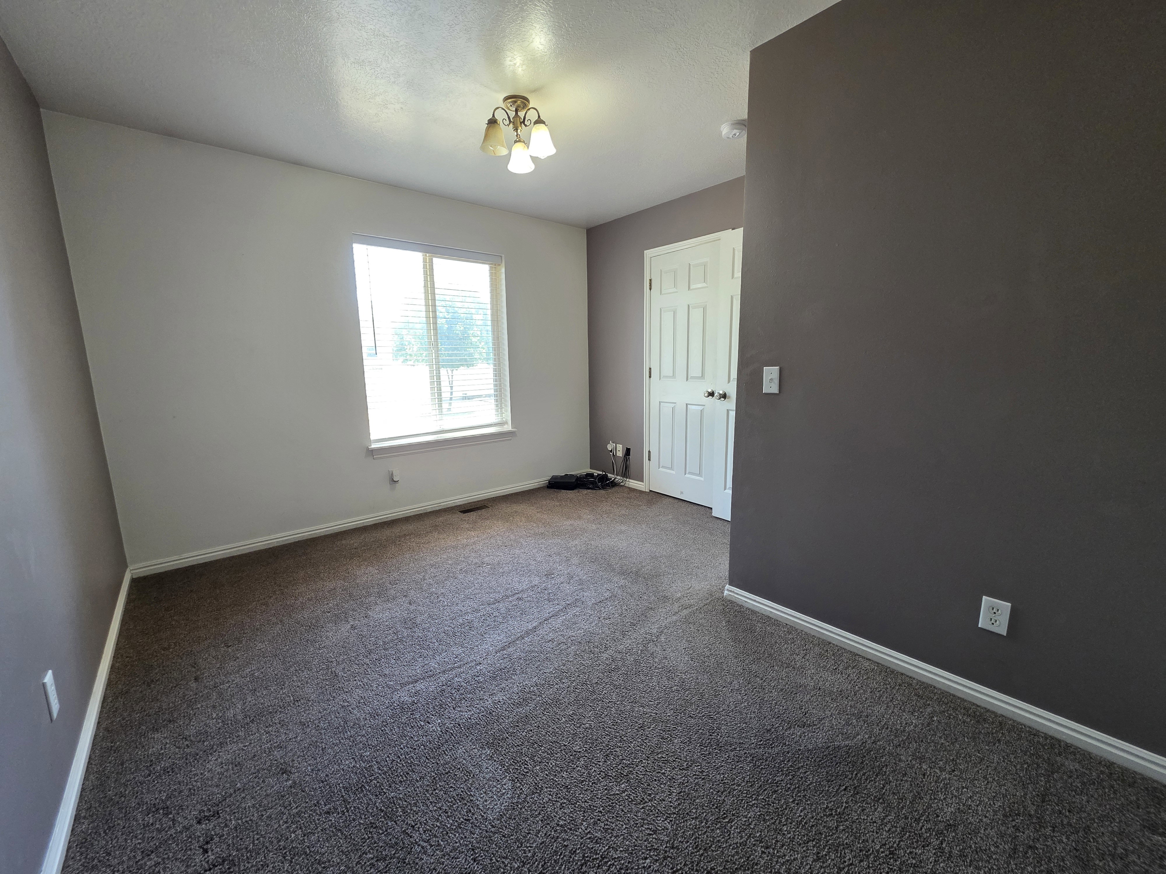 Carpeted room with a multi-pane window featuring blinds