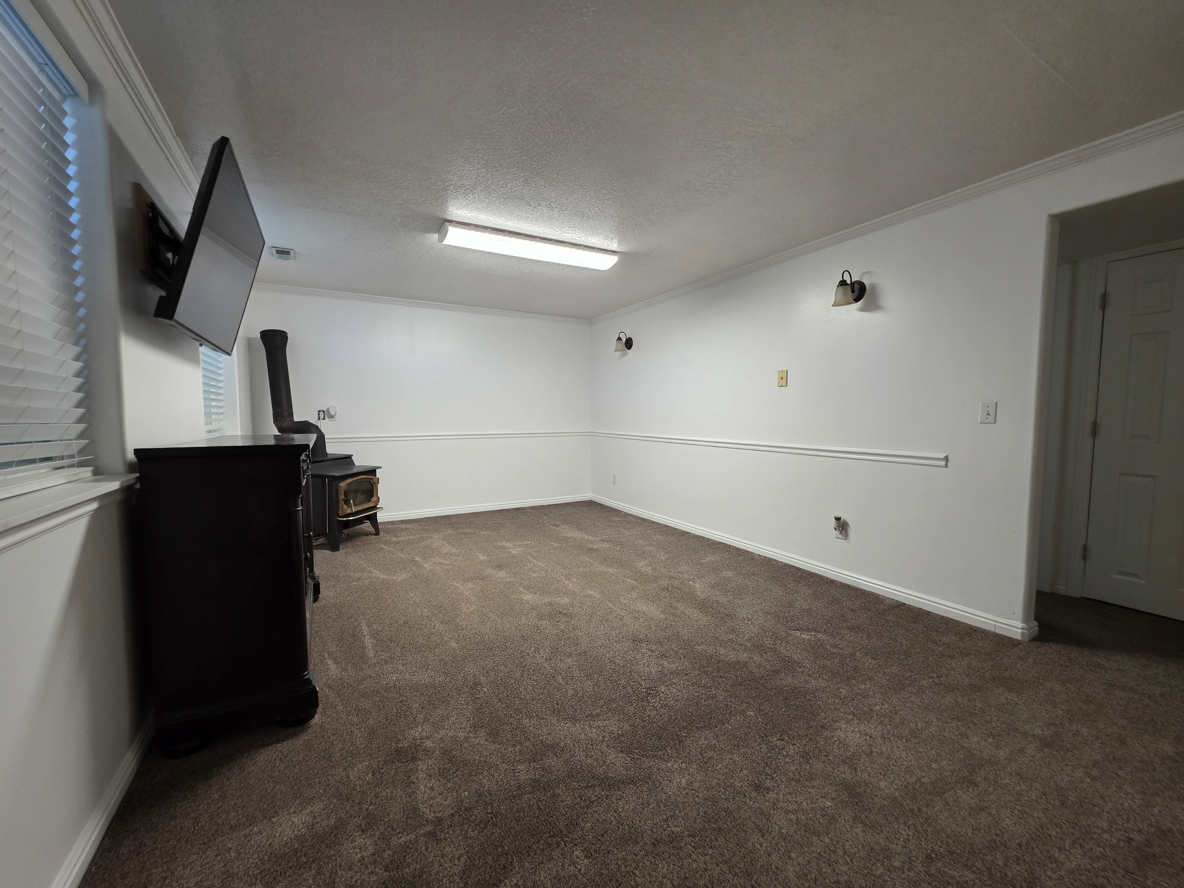 Spacious room featuring neutral carpeting and white walls with chair rail molding