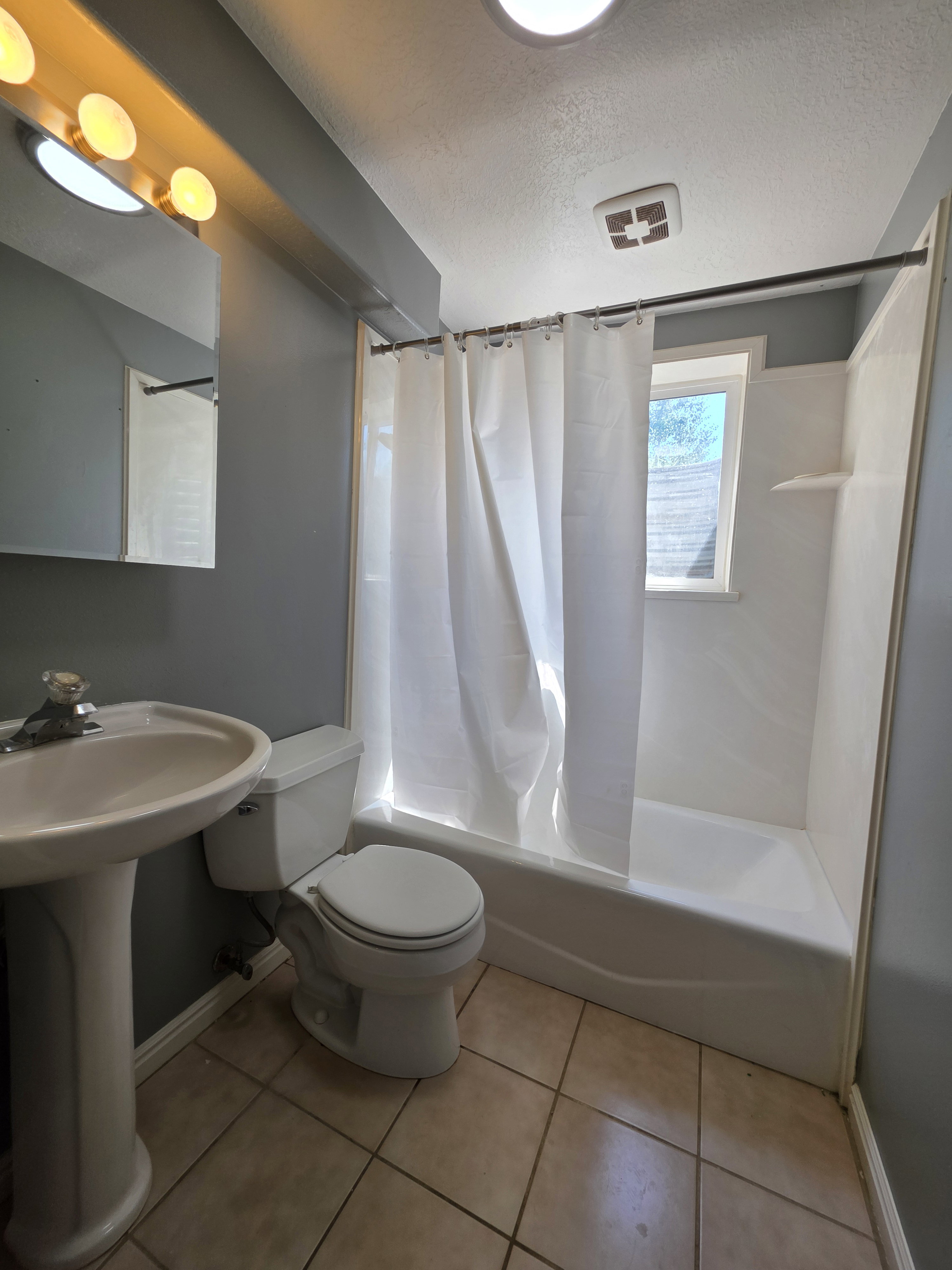 Full bathroom featuring a white pedestal sink, white toilet, and a bathtub with an integrated shower surround