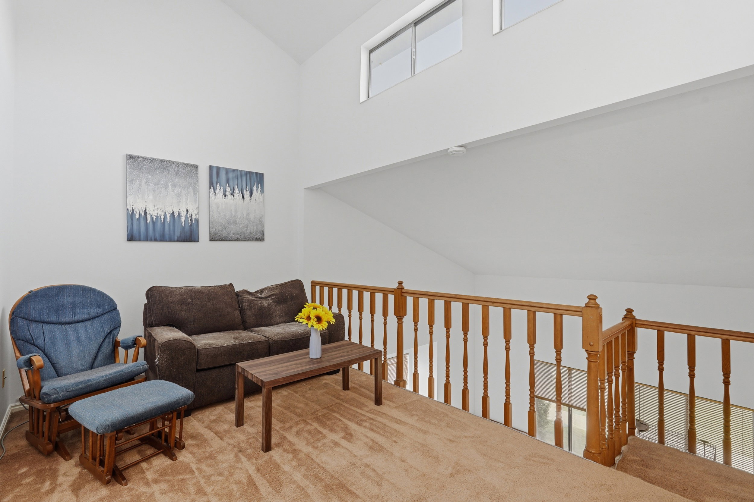 Carpeted loft space with a vaulted ceiling and upper-level transom windows
