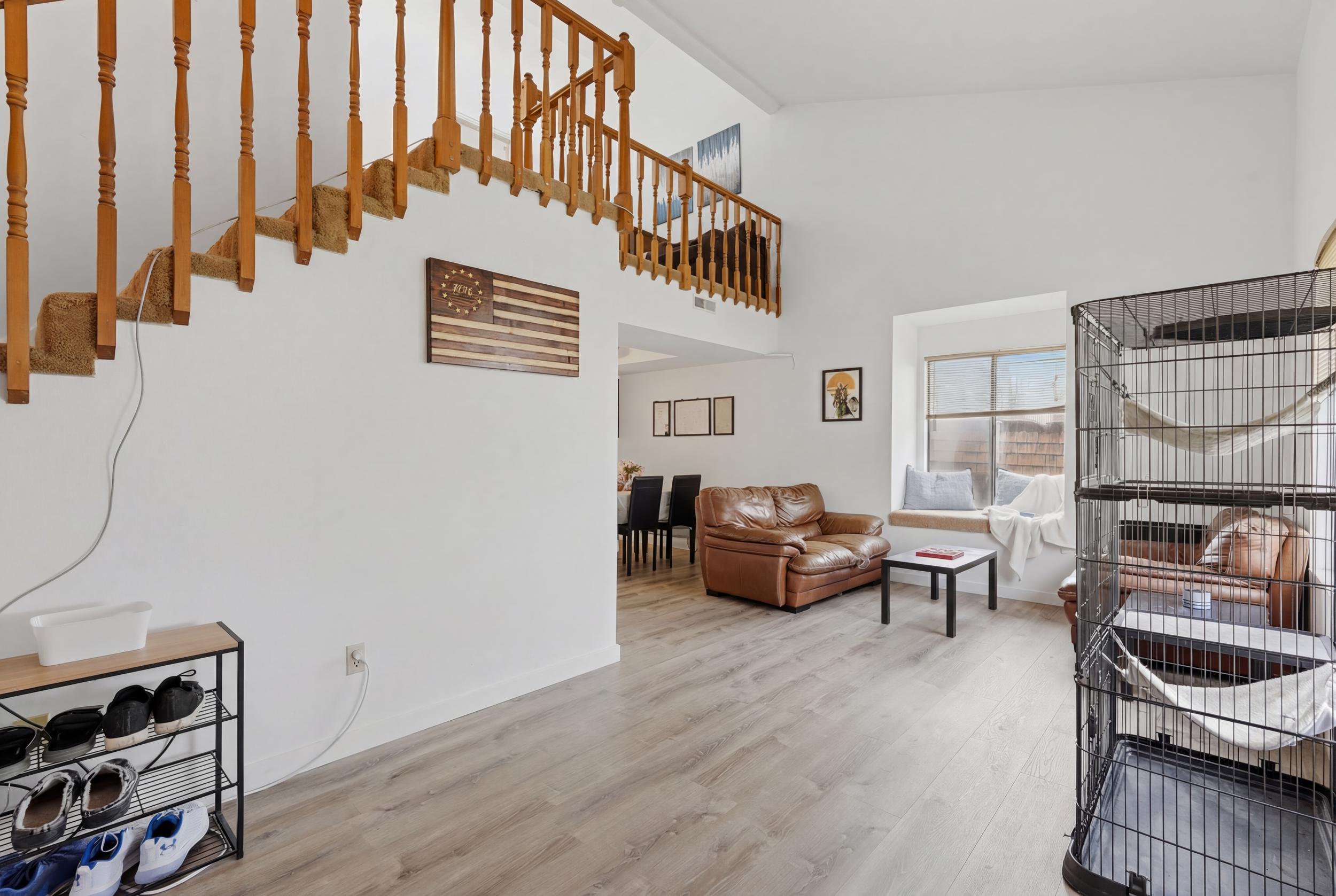 Open-concept living area featuring LVP flooring, a prominent staircase with wood banisters, and a window seat