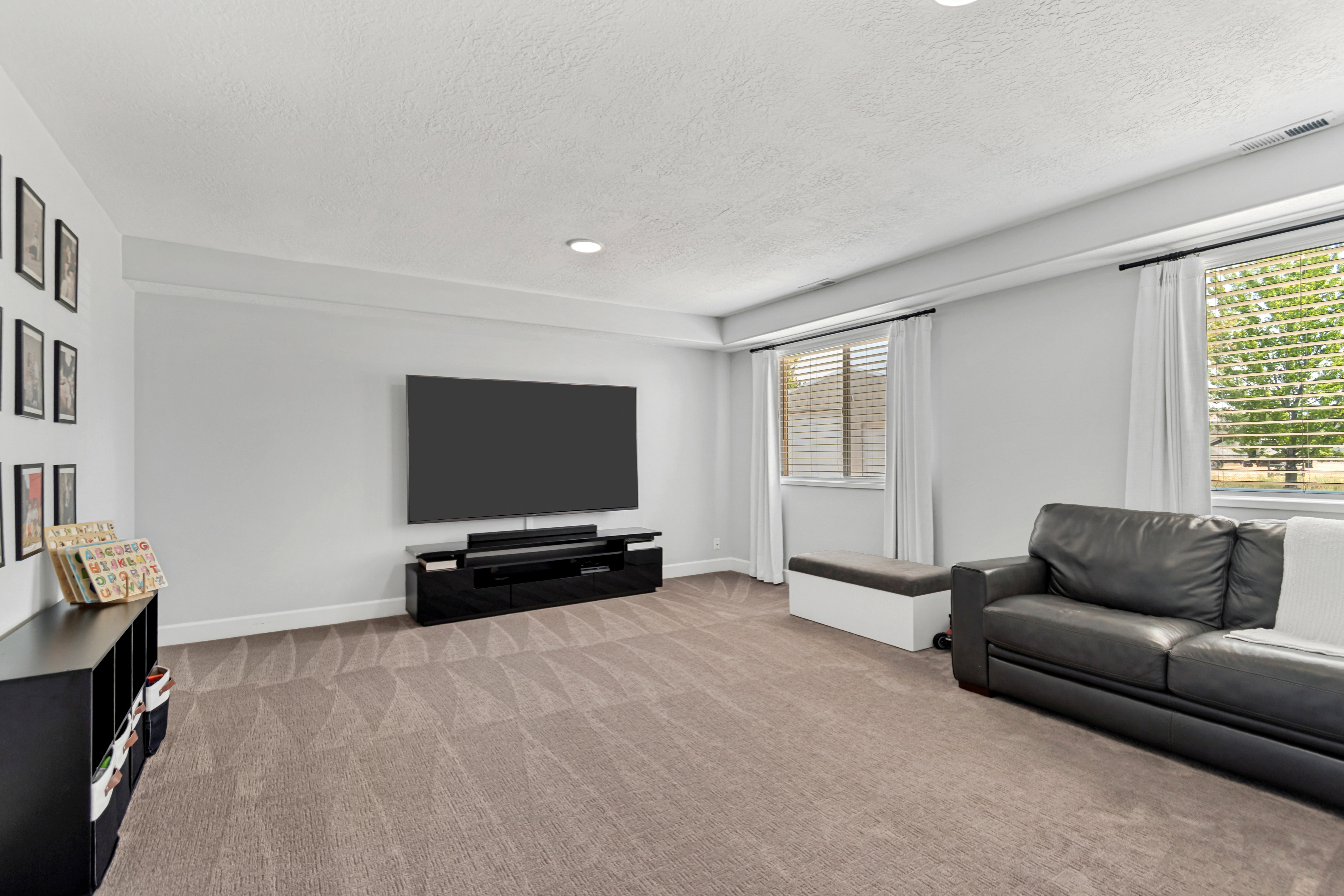 Spacious room featuring neutral carpeting, light gray walls, recessed lighting, and two windows with blinds
