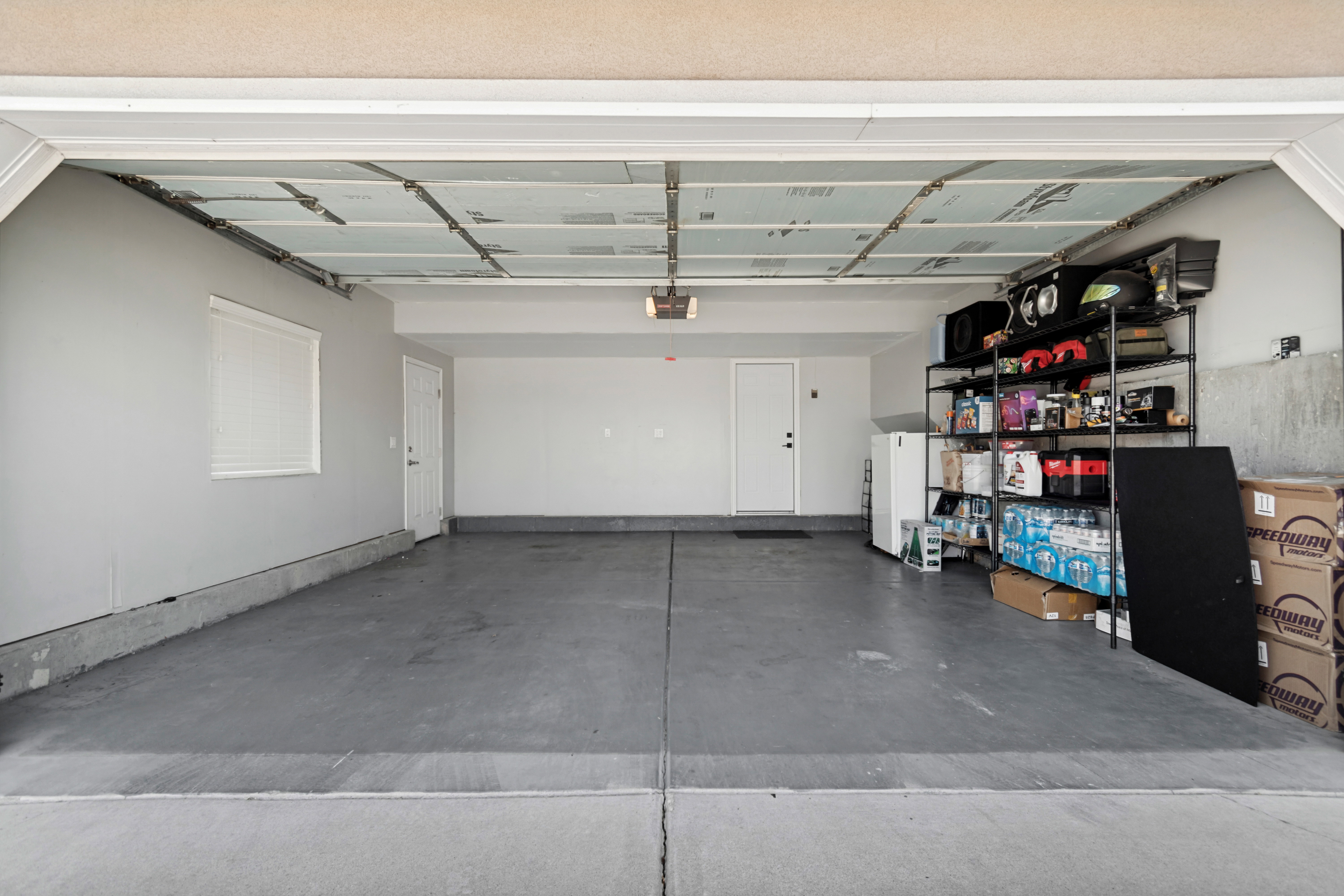 Spacious garage with light gray walls, concrete flooring, and a white window with blinds