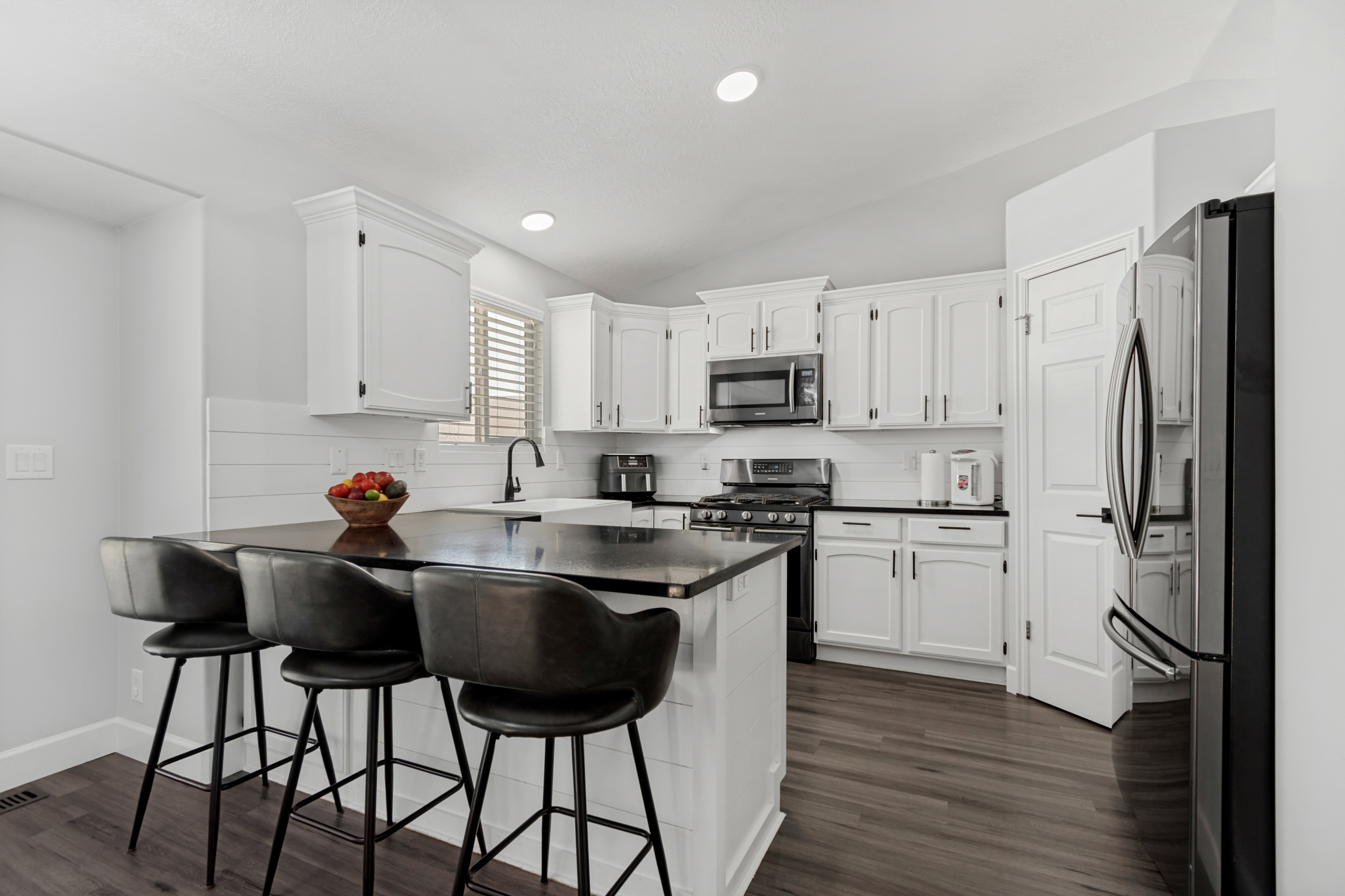 Modern kitchen featuring white cabinetry, dark countertops, and wood-finish flooring