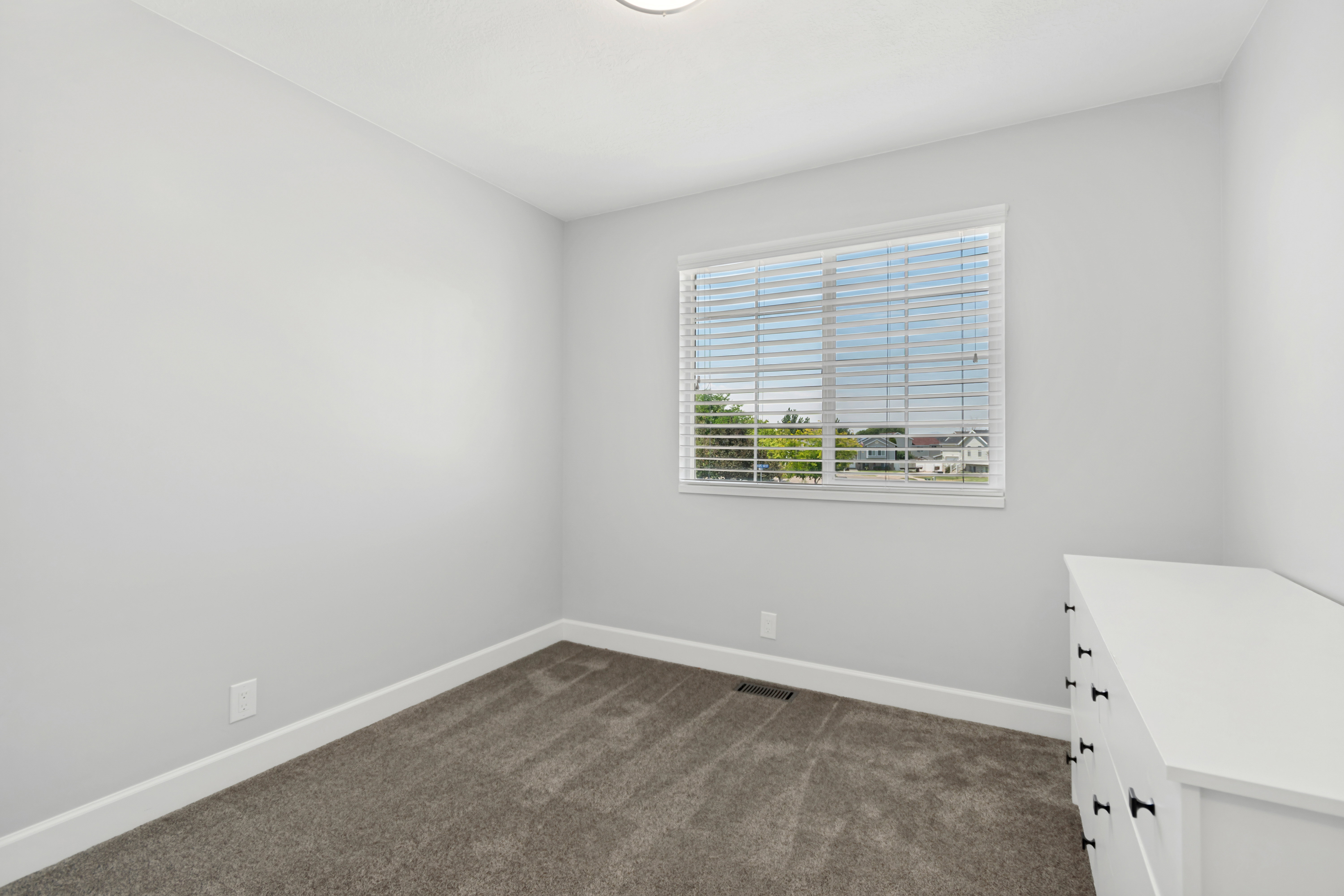 Interior room featuring light gray walls, dark gray carpet flooring, and white trim