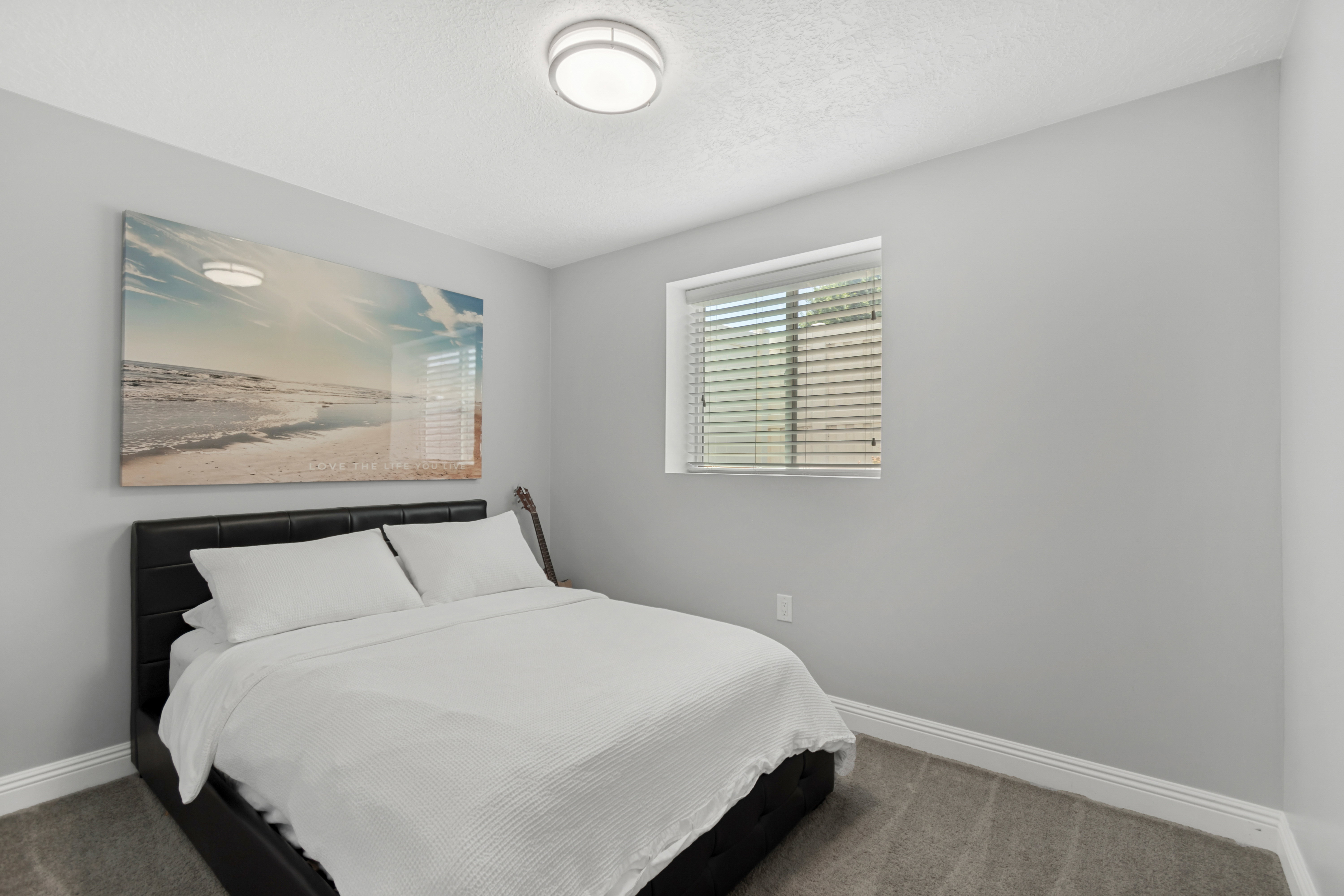 Spacious room featuring light gray wall paint, a window with horizontal blinds, gray carpet flooring, white baseboards, and a flush mount ceiling light fixture
