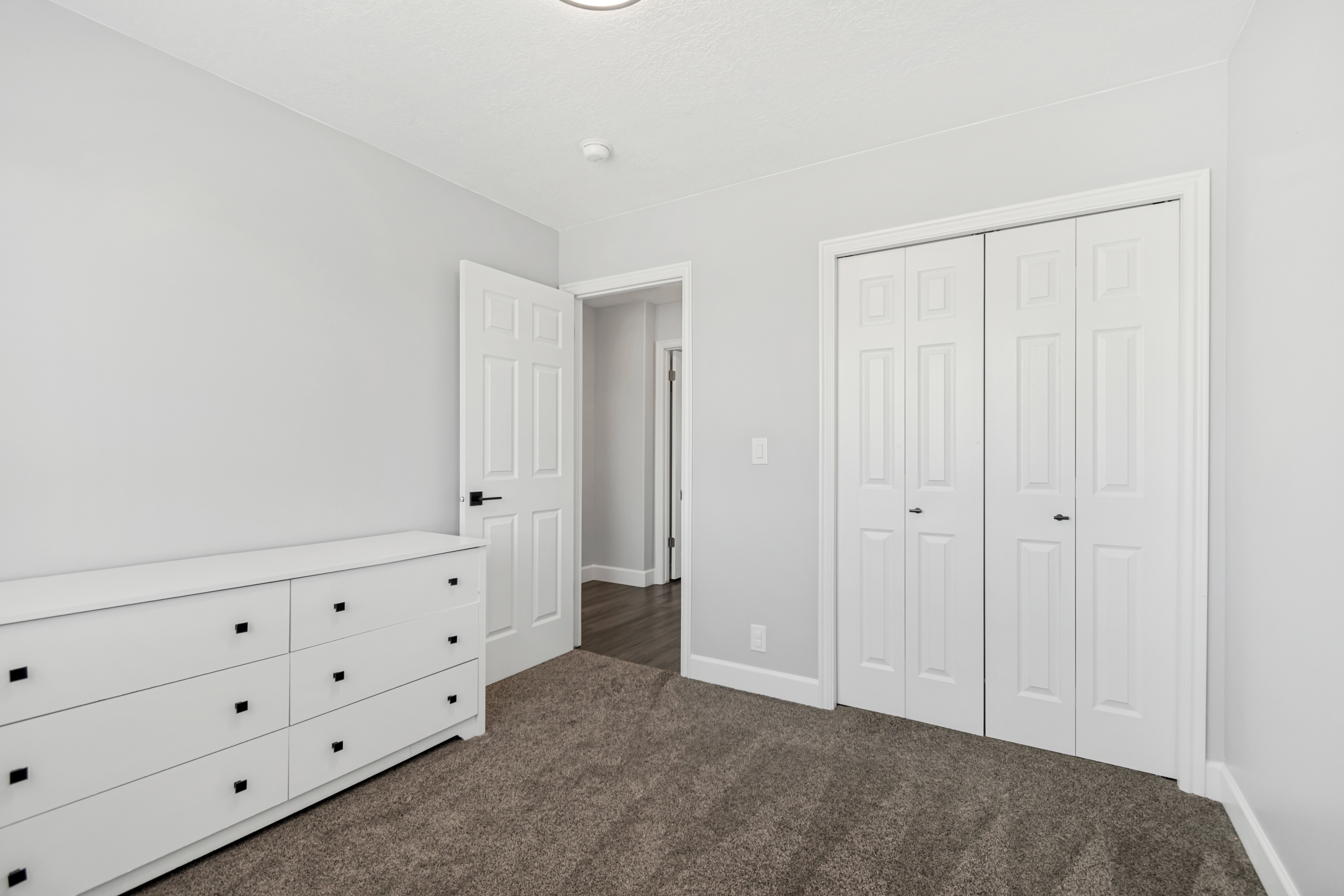 Neutral wall tones with dark carpet flooring, white trim, and a bi-fold closet