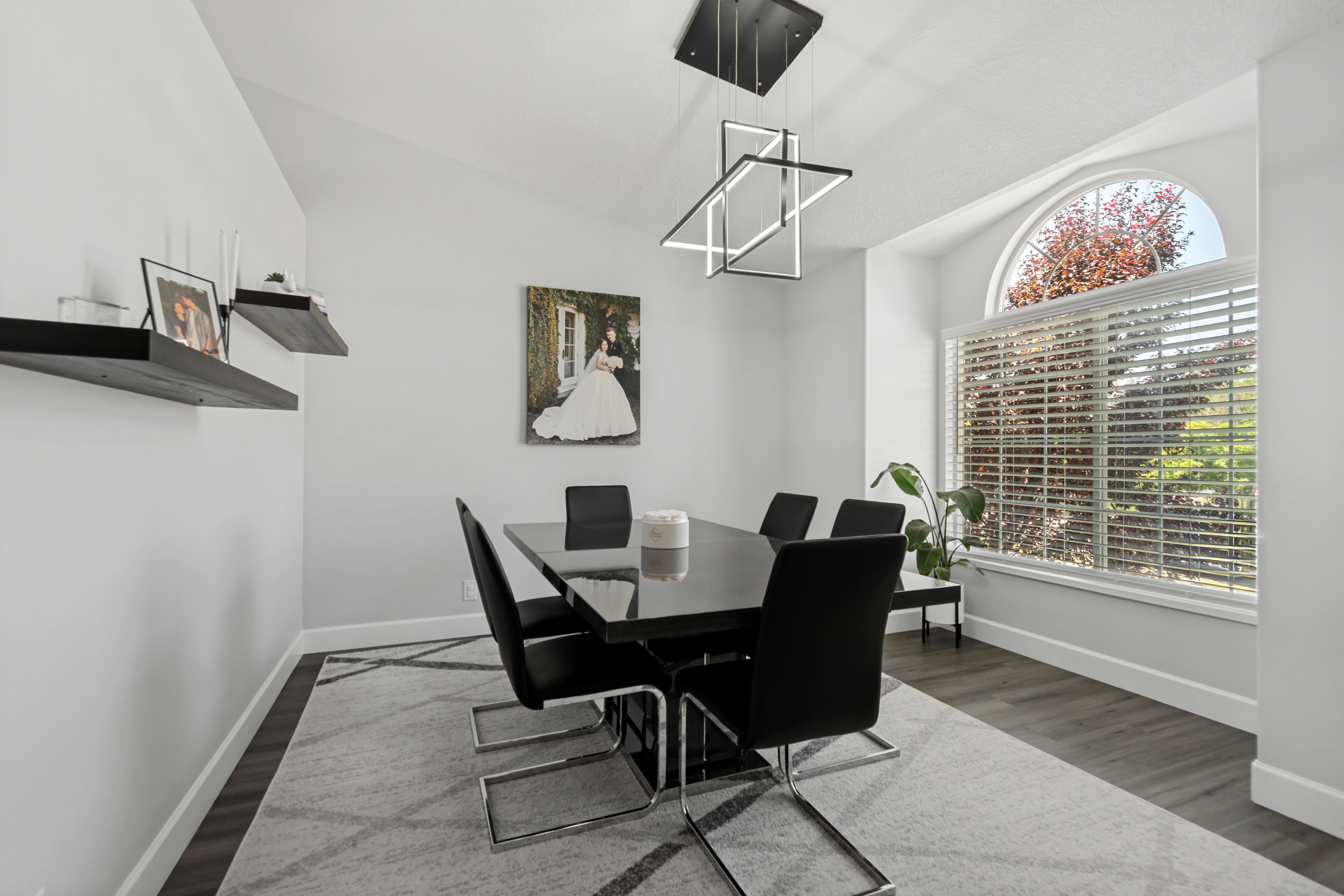 Dining space featuring a large arched window, vaulted ceiling, modern geometric chandelier, and wood-finish flooring