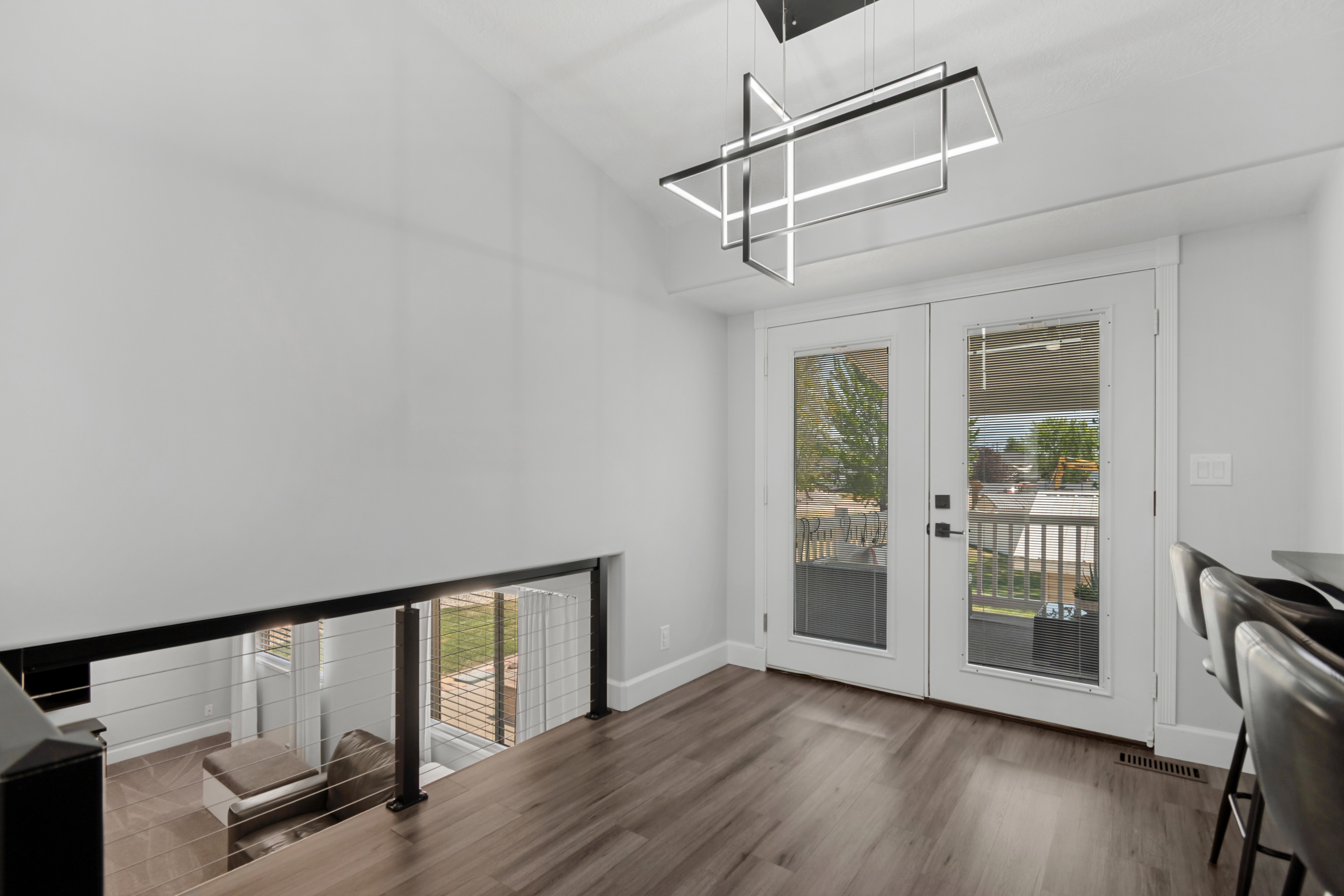 Open-concept space featuring a modern linear chandelier, wood-finish flooring, and white double French doors