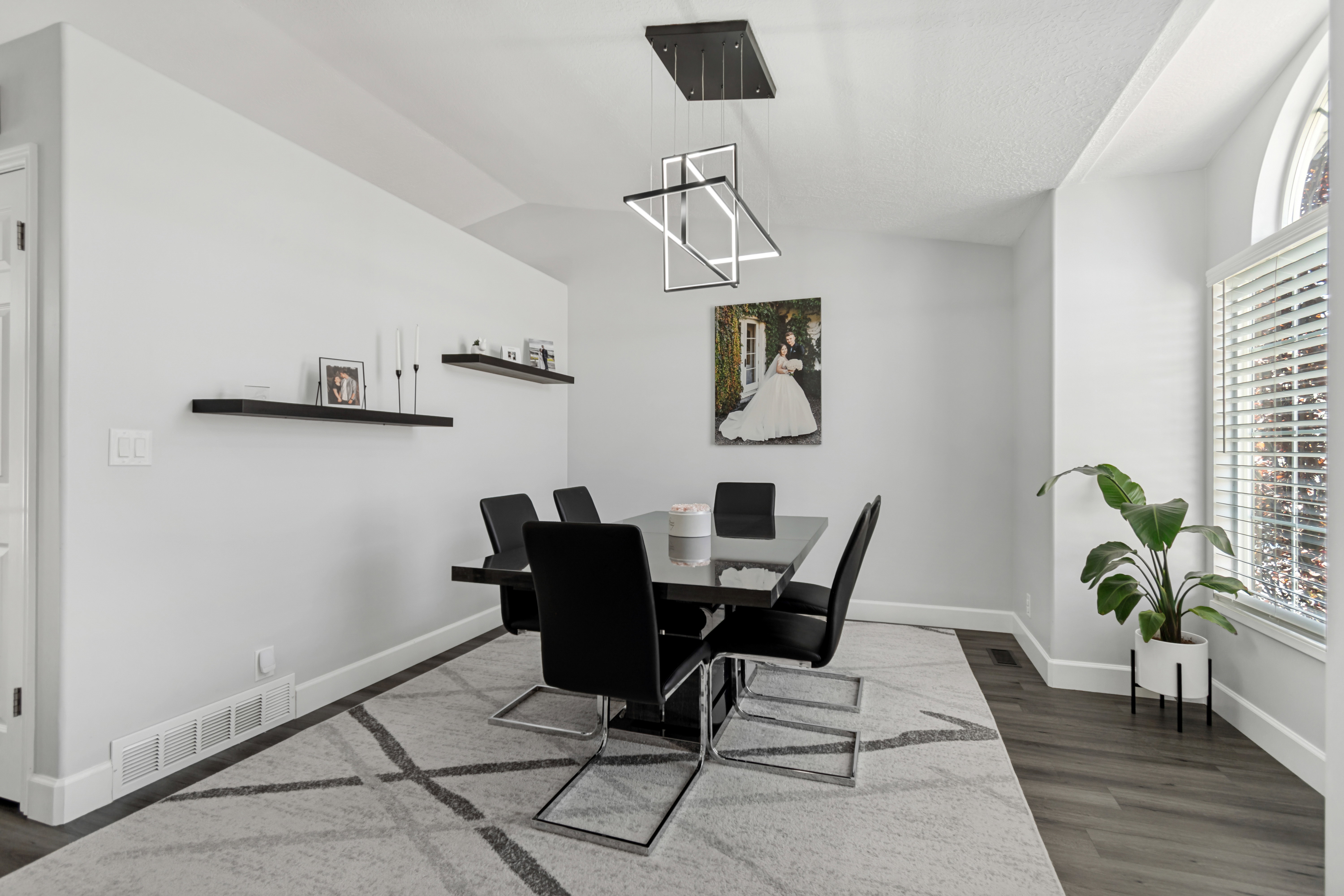 Dining area featuring a contemporary linear chandelier, dark wood-finish flooring, a large arched window with blinds, and white baseboards