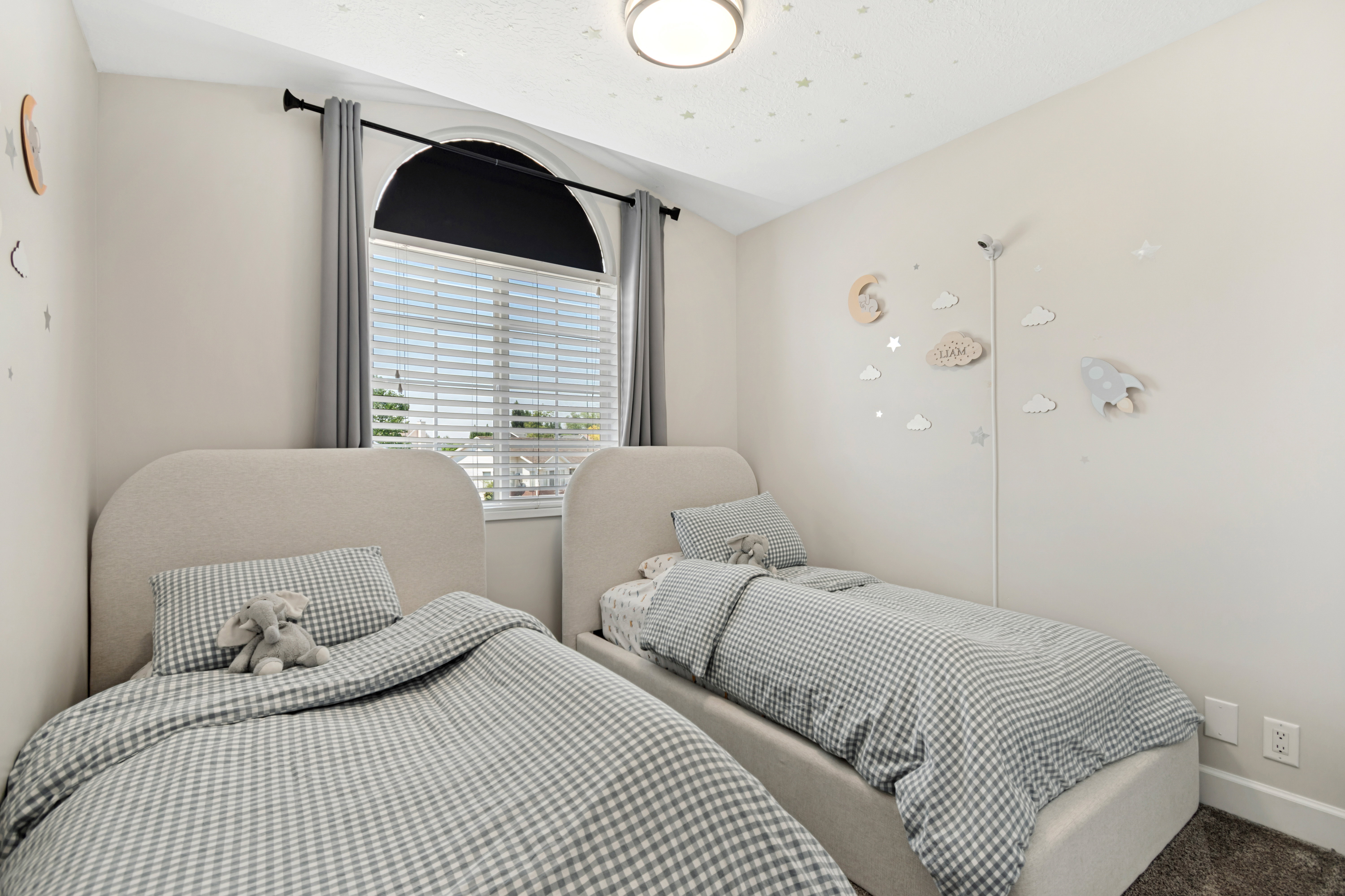 Bedroom featuring a large arched window with blinds, a flush mount ceiling light, and light-toned walls