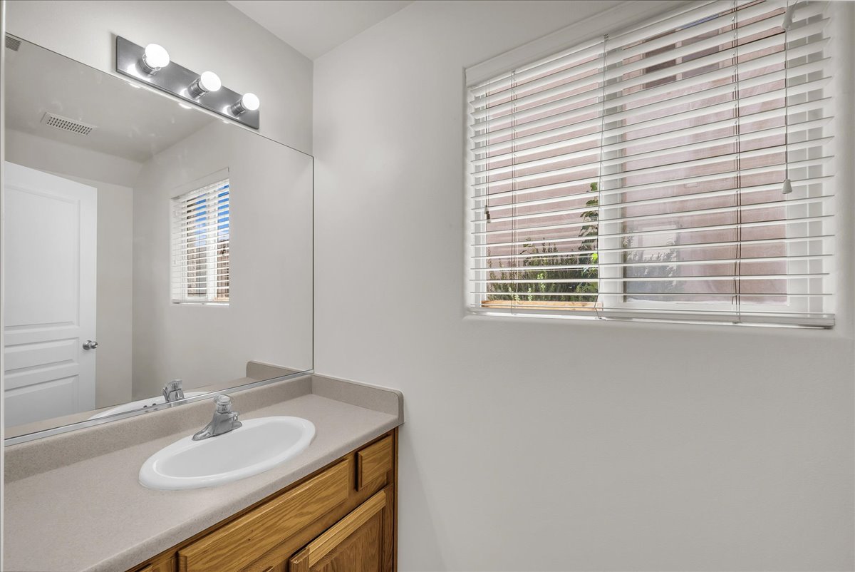 Bright vanity area with natural light, light wood cabinetry, an integrated sink, and ample storage.