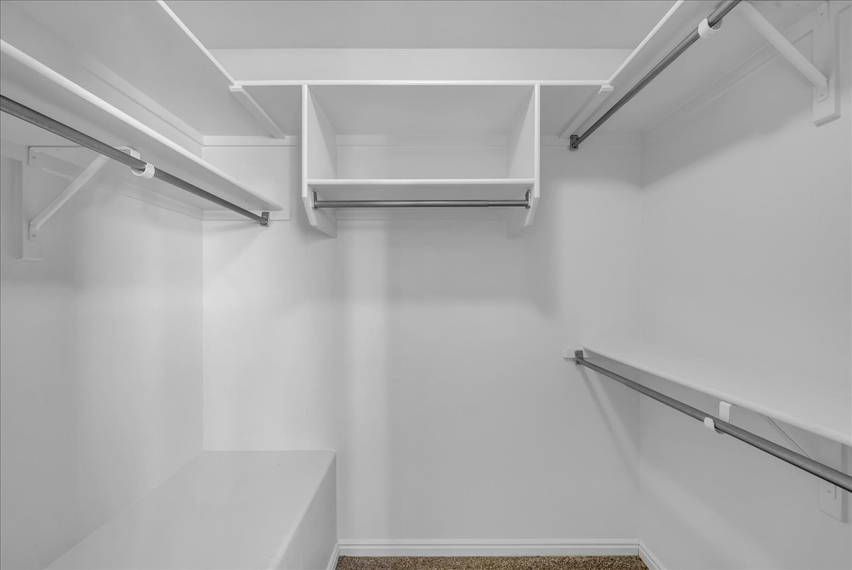 Generous walk-in closet with built-in shelving, multiple hanging rods, and plenty of room to stay organized.