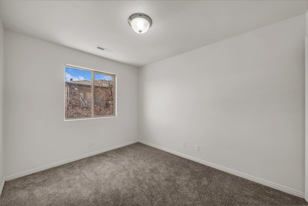 Comfortable secondary bedroom with plush carpeting, abundant natural light, and neutral finishes that complement any style.