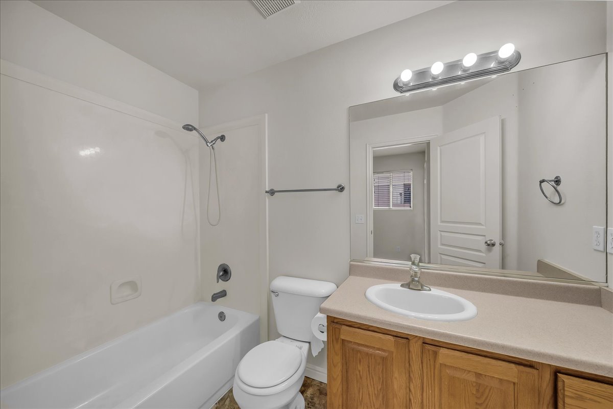 Clean, functional full bathroom with a wood-finish vanity and generous counter space.