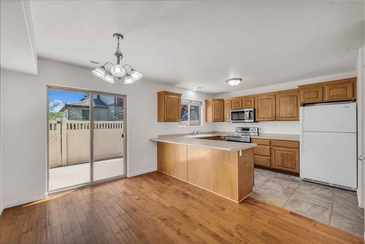 Spacious open-concept kitchen with modern wood cabinetry, wood-finish flooring, and seamless flow into the dining area, complete with a sliding glass door leading to the patio.