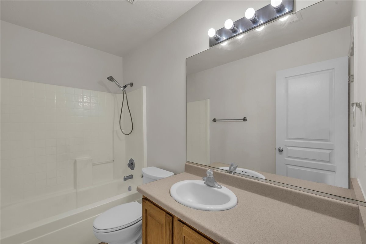 Private en-suite bathroom featuring a full tub and shower combination, plus a wood-finish vanity with generous counter space.