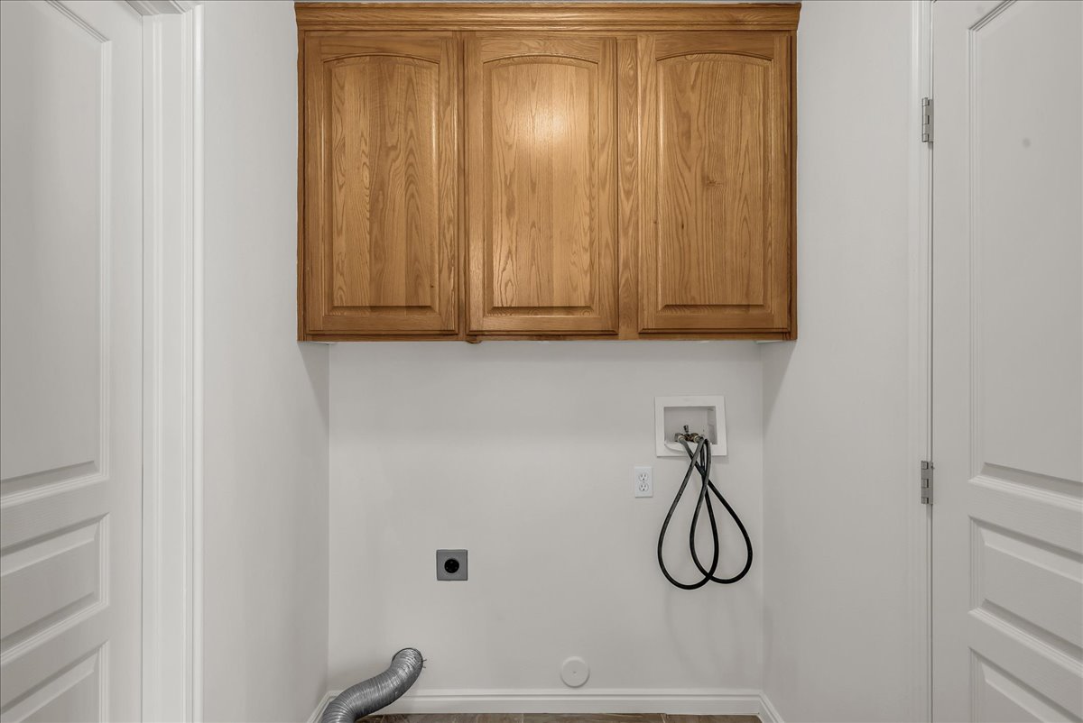 Dedicated laundry room with overhead cabinetry and utility hookups, offering added storage and everyday convenience.