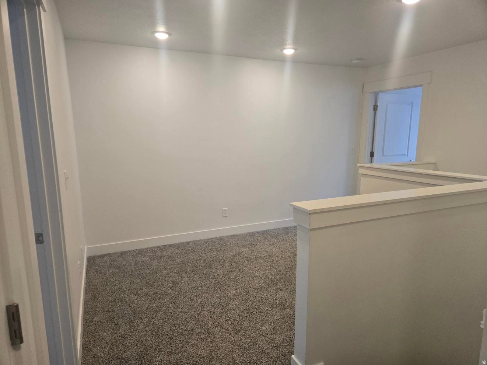 Open concept room featuring recessed lighting, light gray carpeting, crisp white walls, and a white balustrade