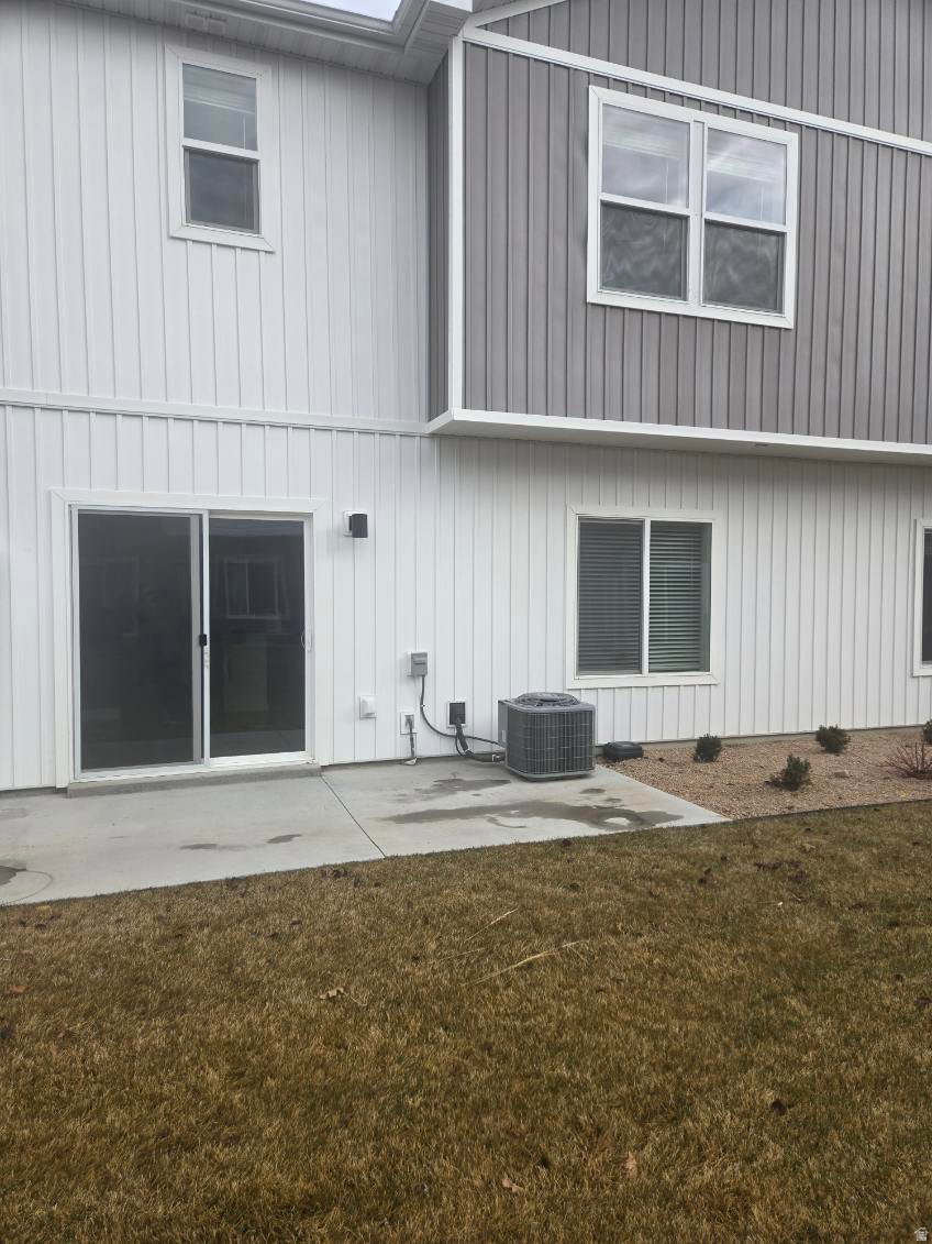 Rear exterior featuring a concrete patio, sliding glass door, and white vertical siding