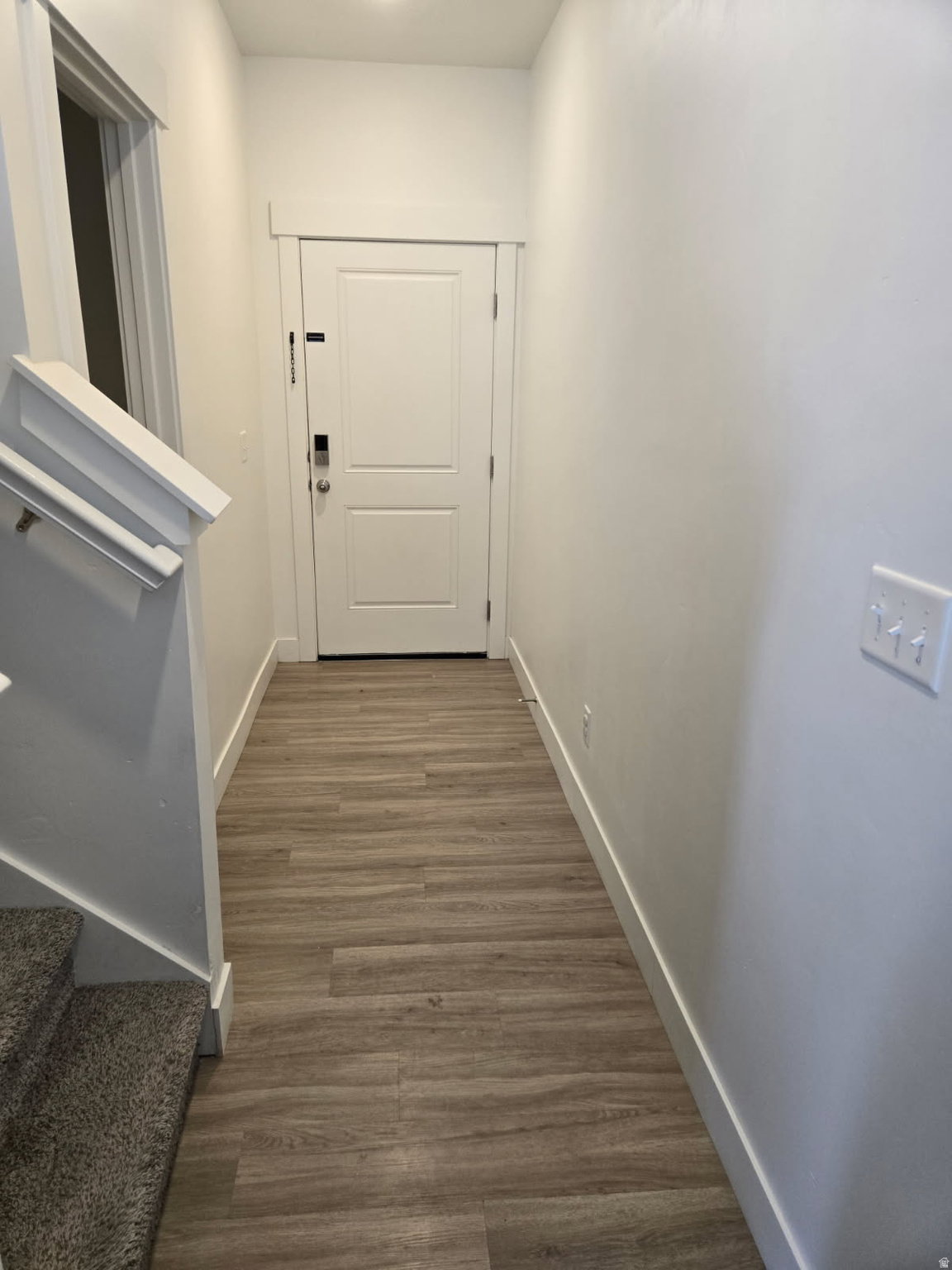 Entryway featuring wood-finish flooring, crisp white walls, and a recessed ceiling light