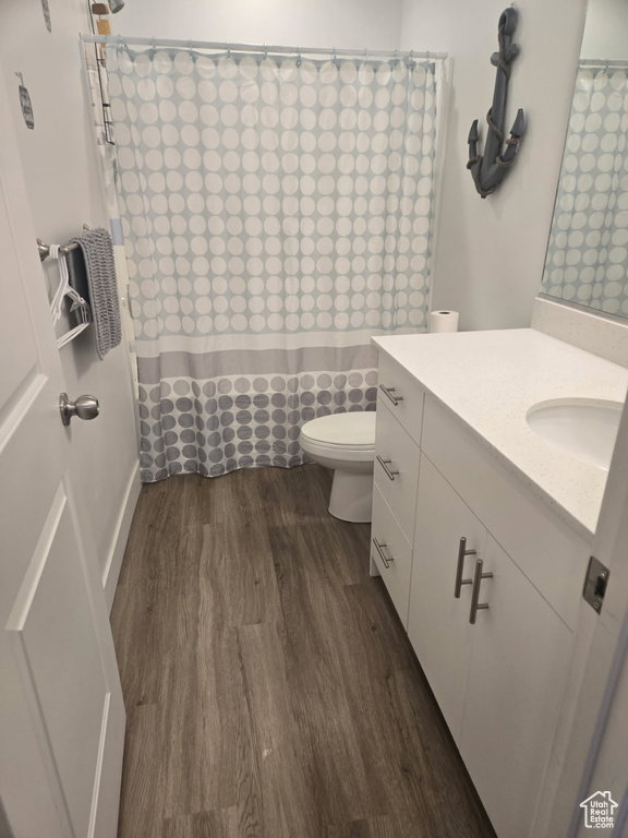 Contemporary bathroom featuring wood-finish flooring, a white vanity with brushed nickel hardware, and a white countertop with an integrated sink