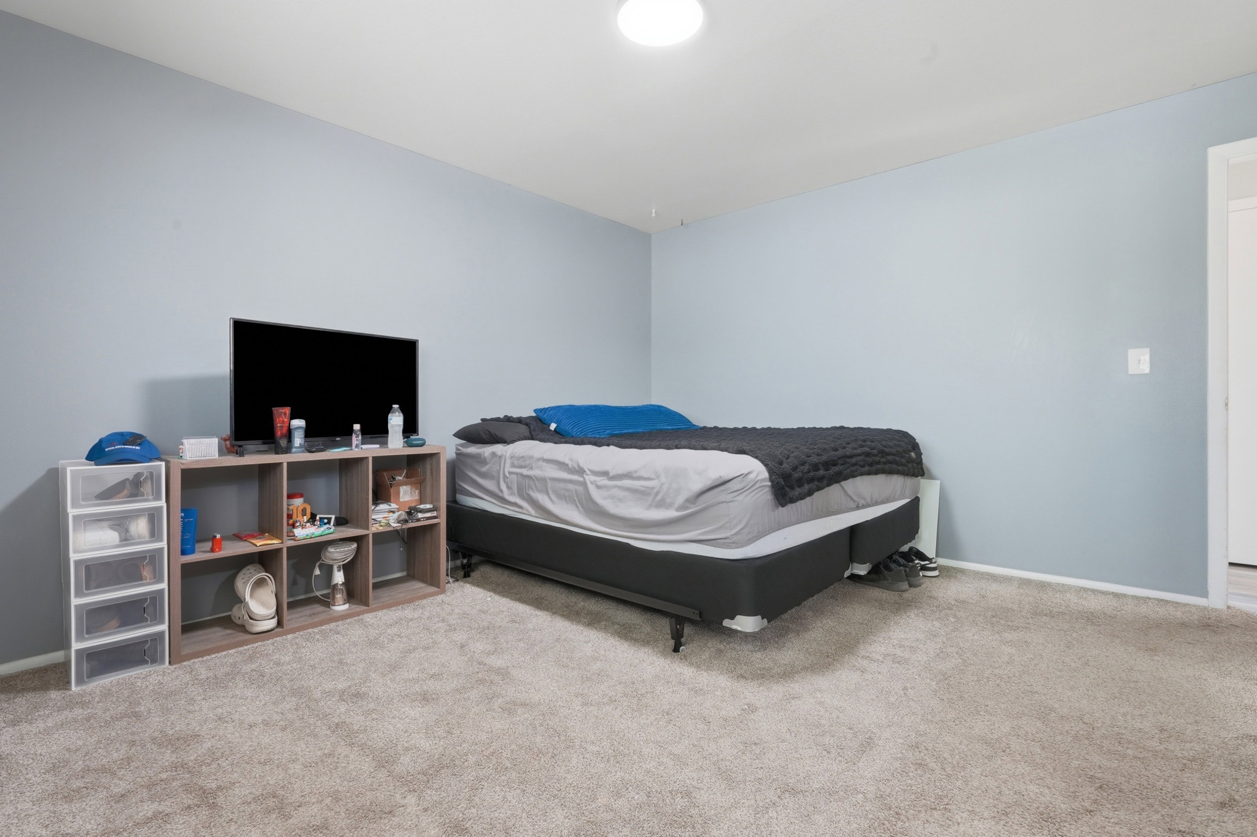 Spacious room featuring light blue walls, neutral-toned carpeting, and white baseboards