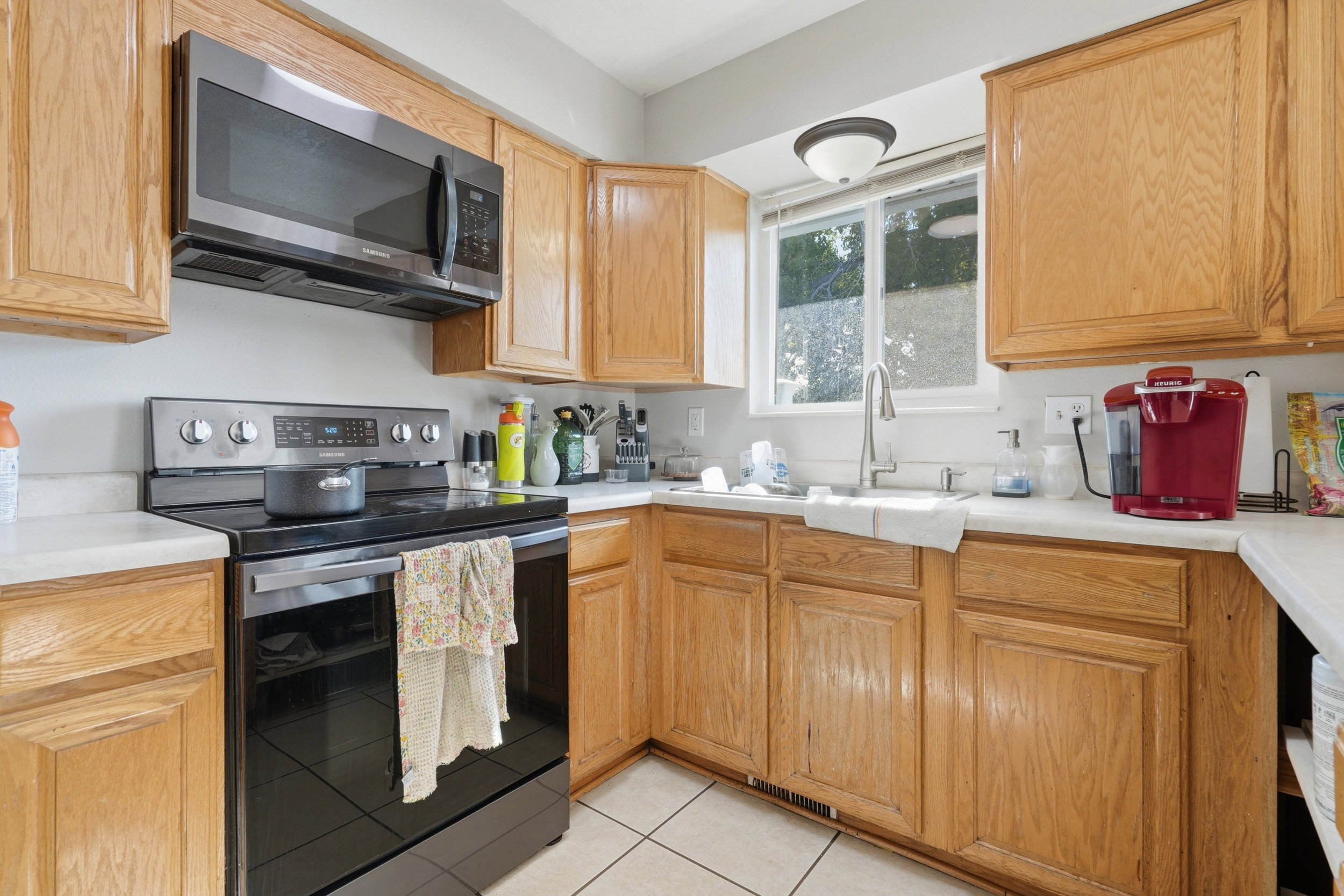 Full kitchen featuring light wood cabinetry, white countertops, stainless steel appliances, and a window above the sink