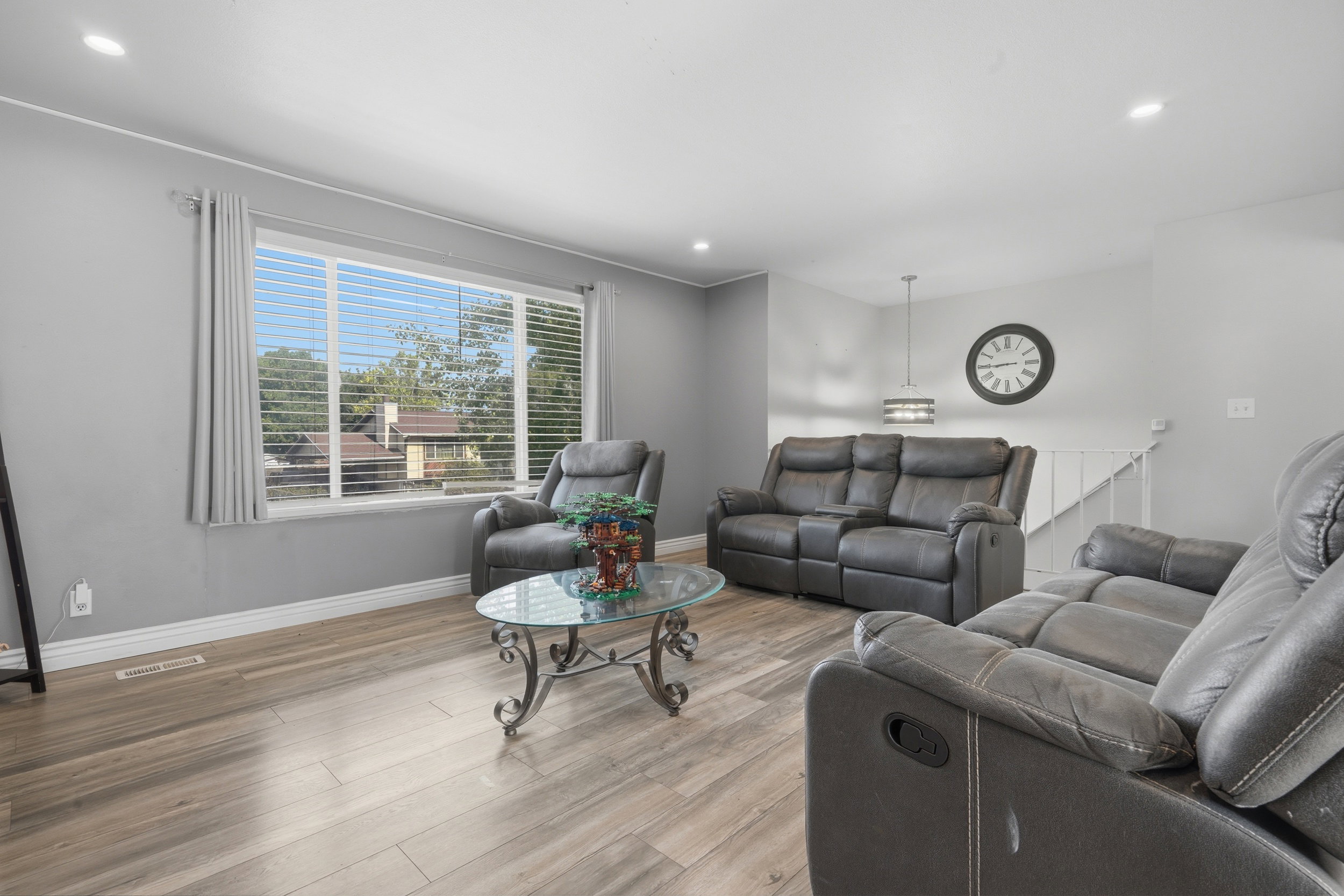 Spacious living area featuring wood-finish flooring, light gray walls, and recessed lighting