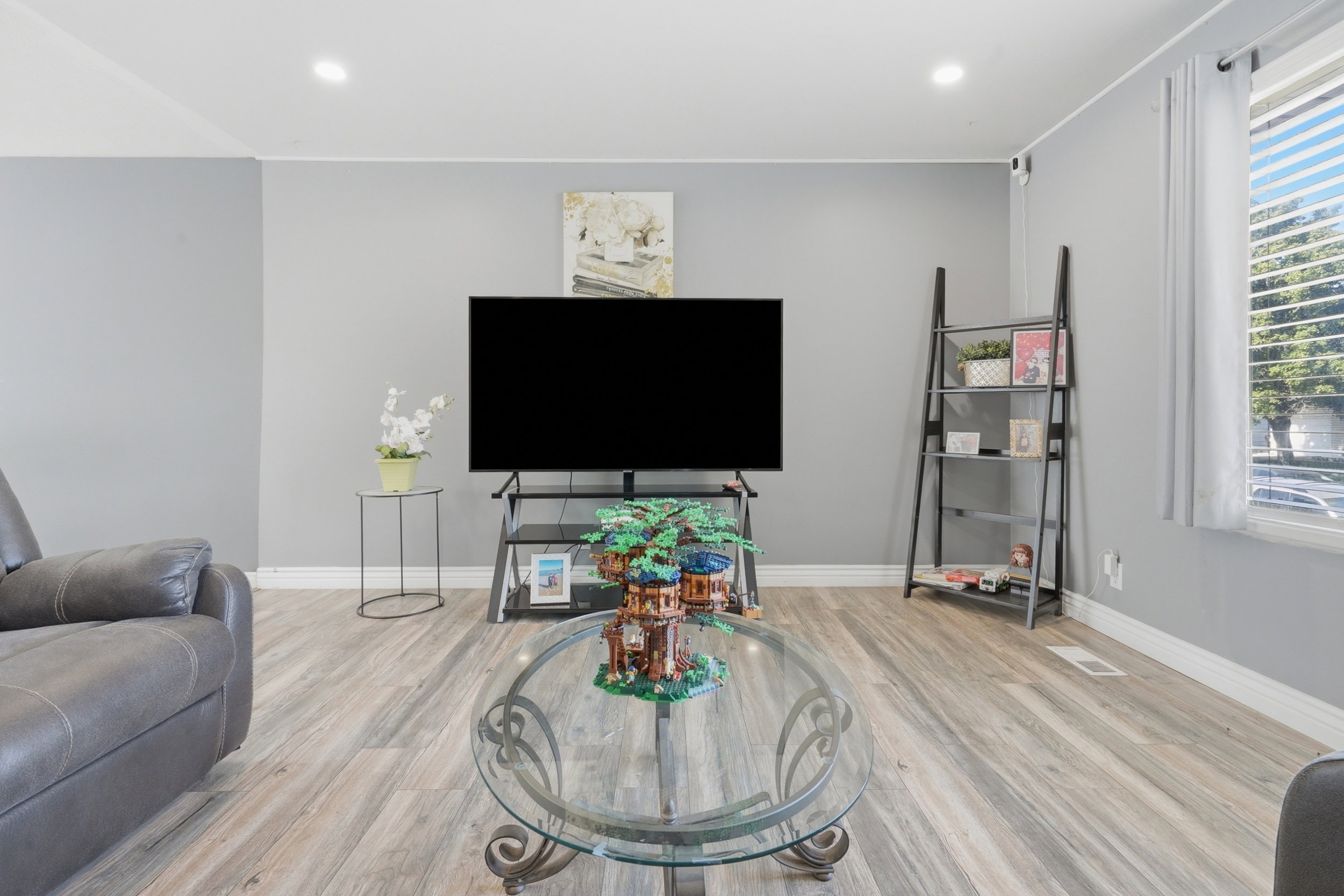 Living area featuring wood-finish flooring, recessed lighting, and ample natural light from a window with blinds
