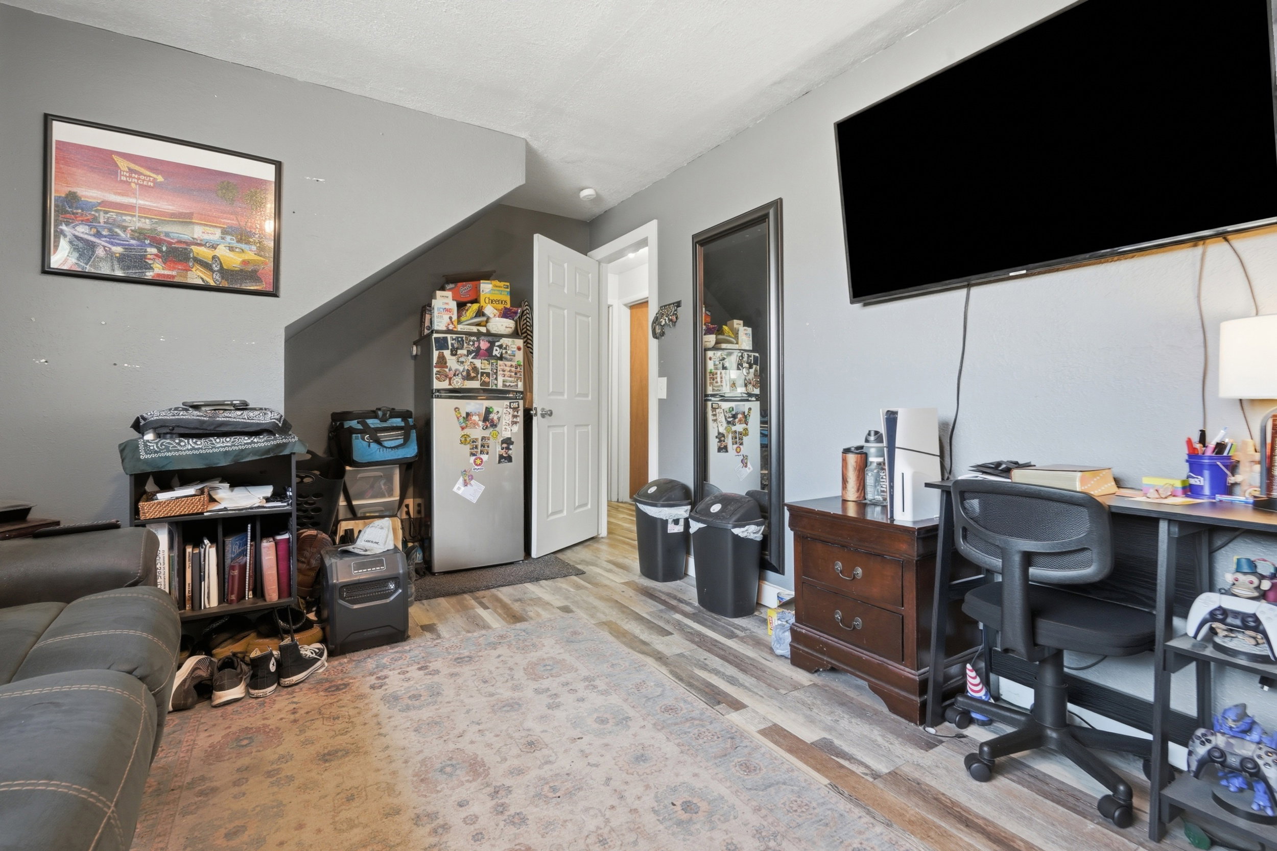 Living area featuring wood-finish flooring, light gray wall paint, and a built-in wall-mounted television