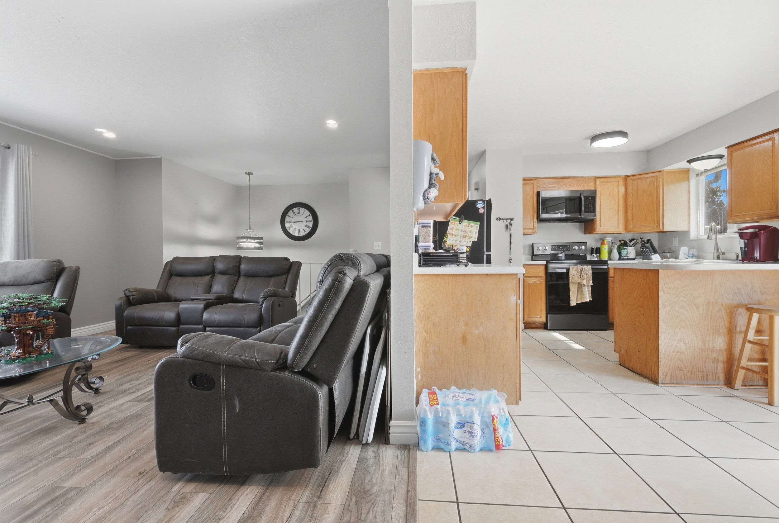 Open-concept living area with wood-finish flooring transitioning to a kitchen with tile flooring