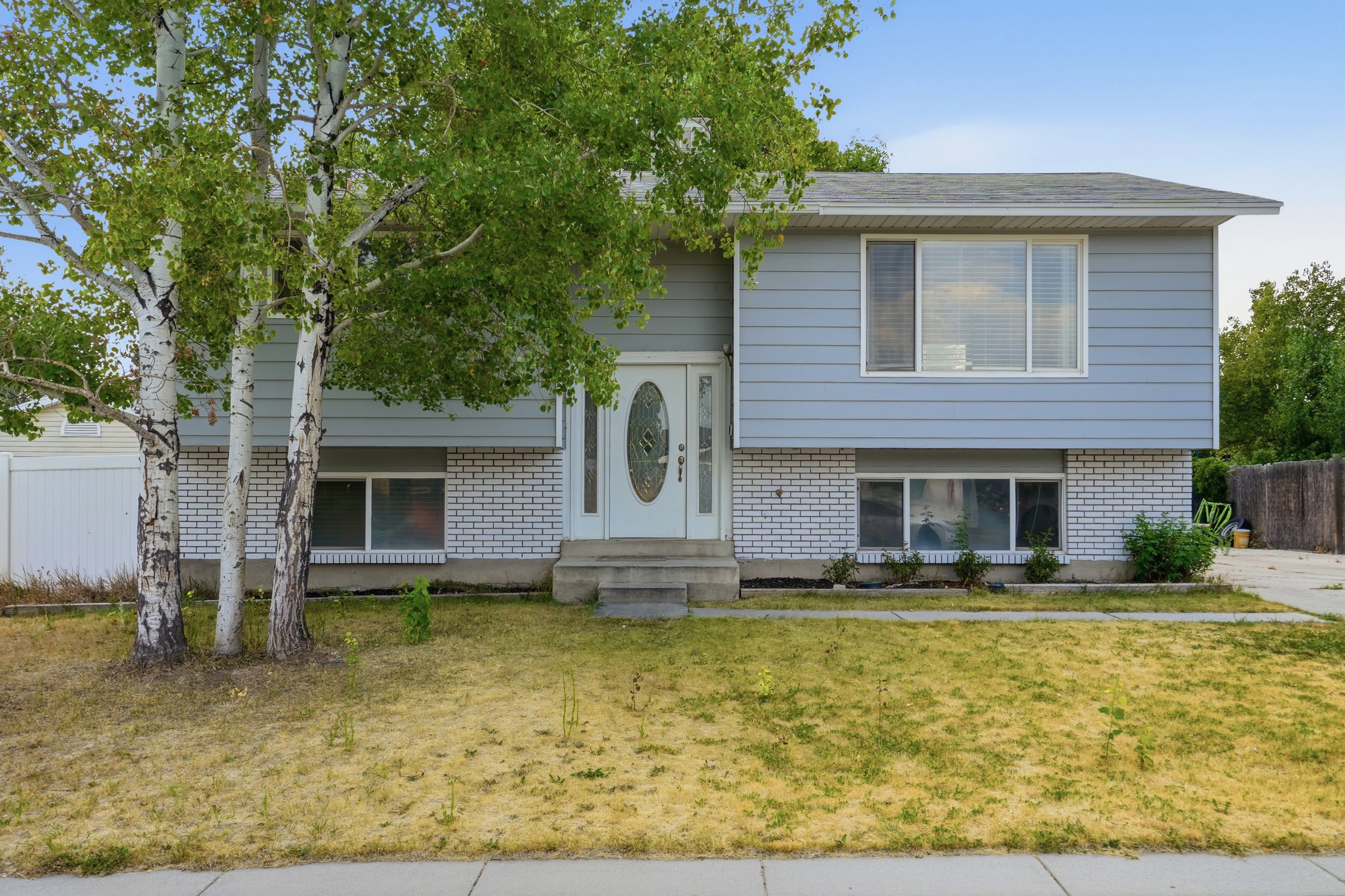 Split-level exterior featuring light blue siding and white brick accents