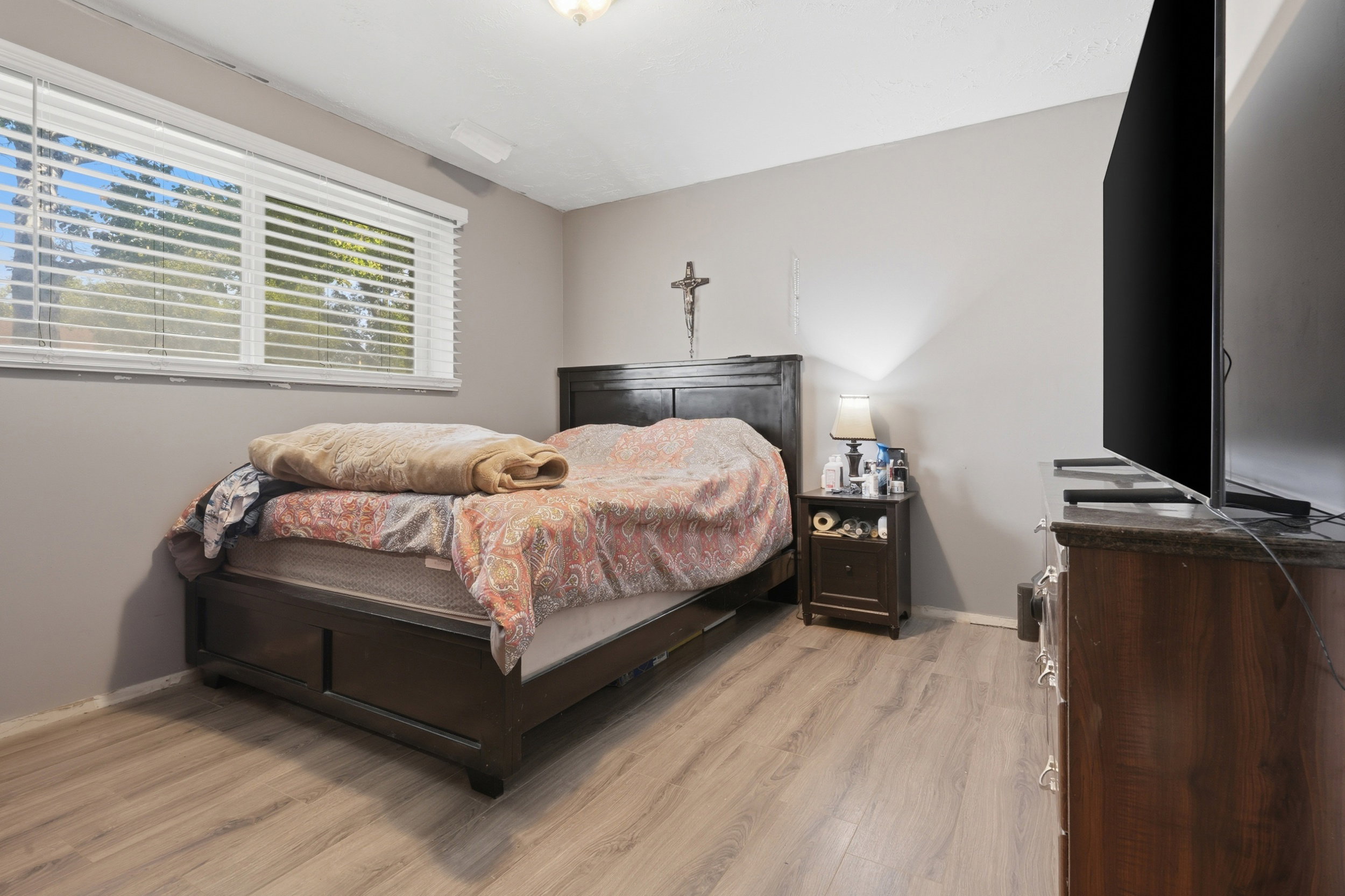 Bedroom featuring wood-finish flooring, a double window with blinds, and neutral-toned walls