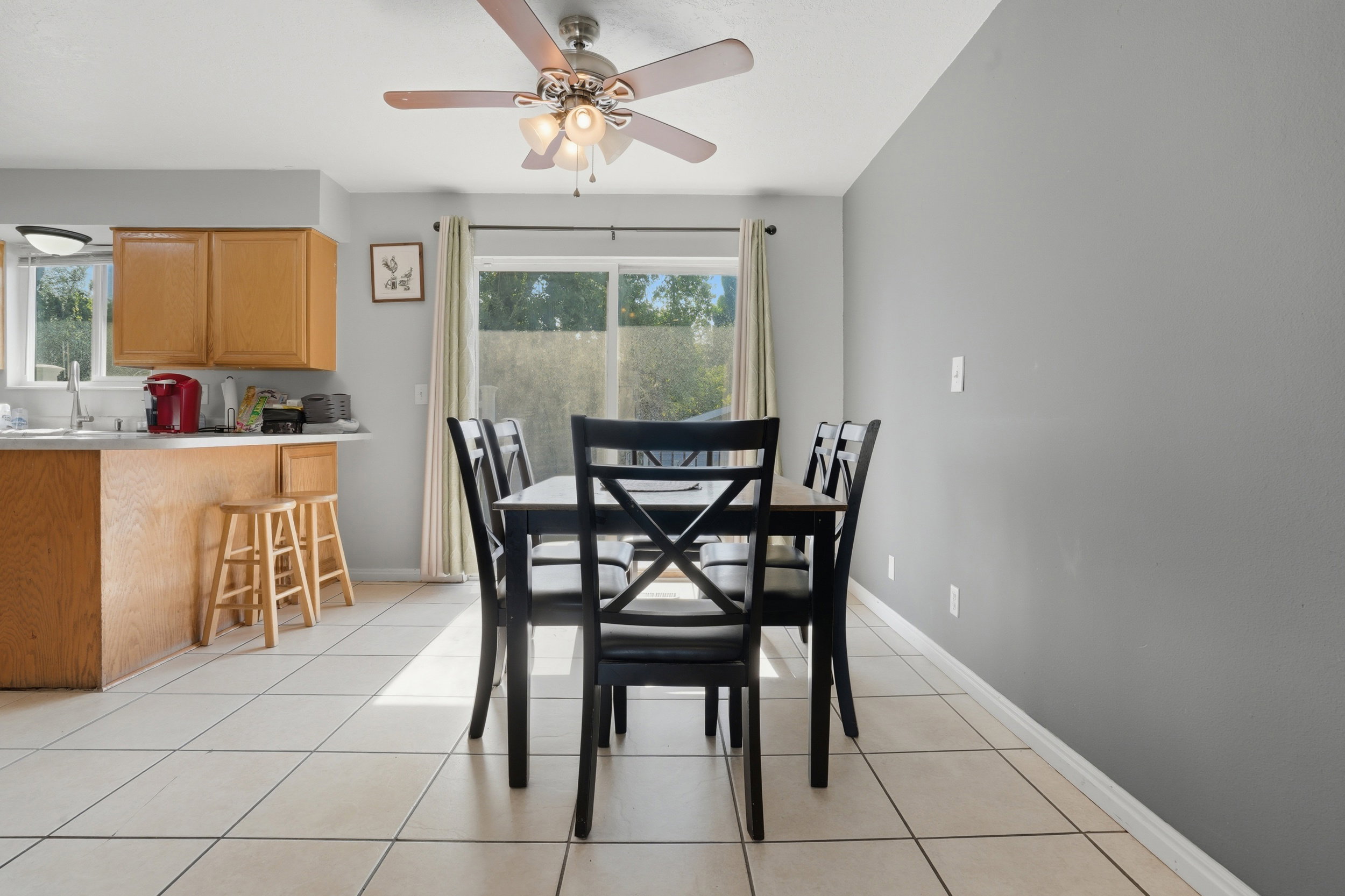 Open-concept dining area featuring light-colored tile flooring and a ceiling fan