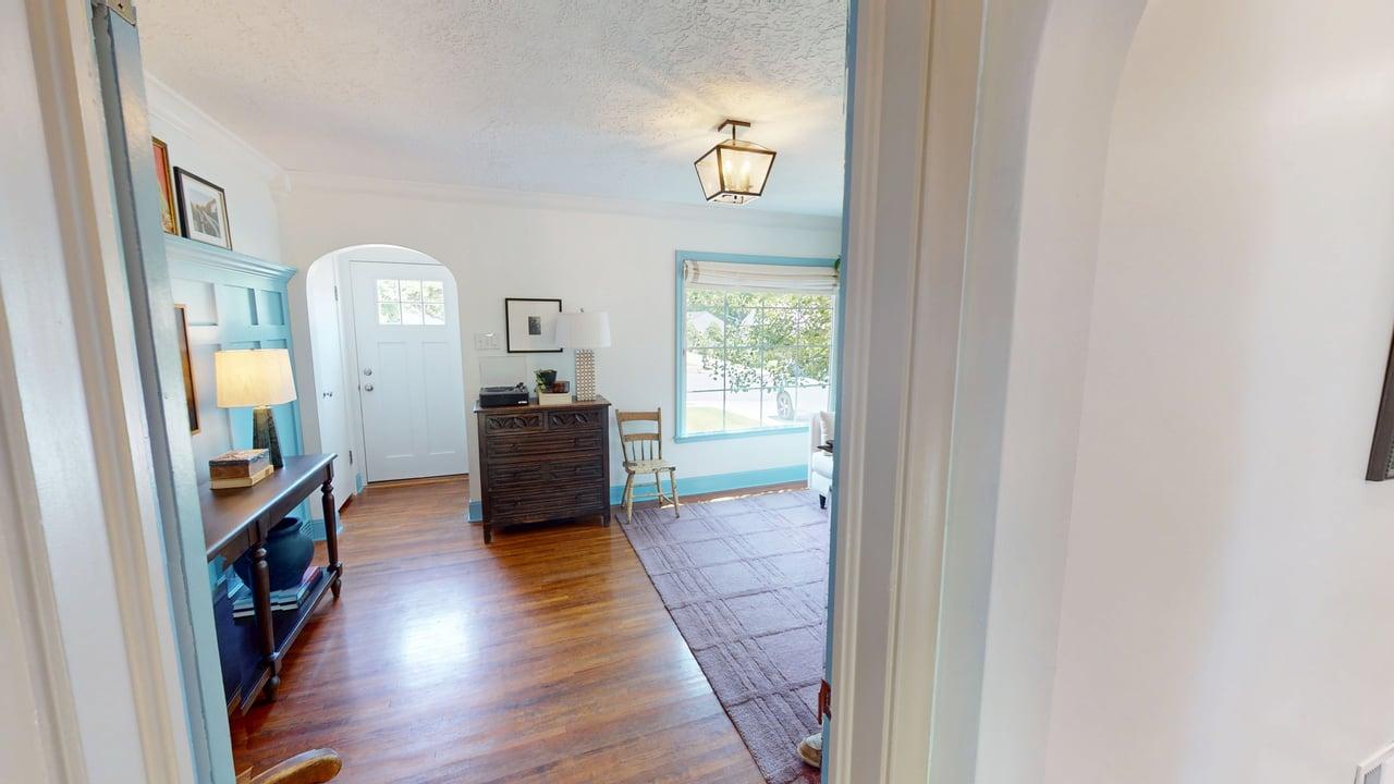 Entryway featuring wood-finish flooring, a white paneled entry door with transom window, and an arched doorway