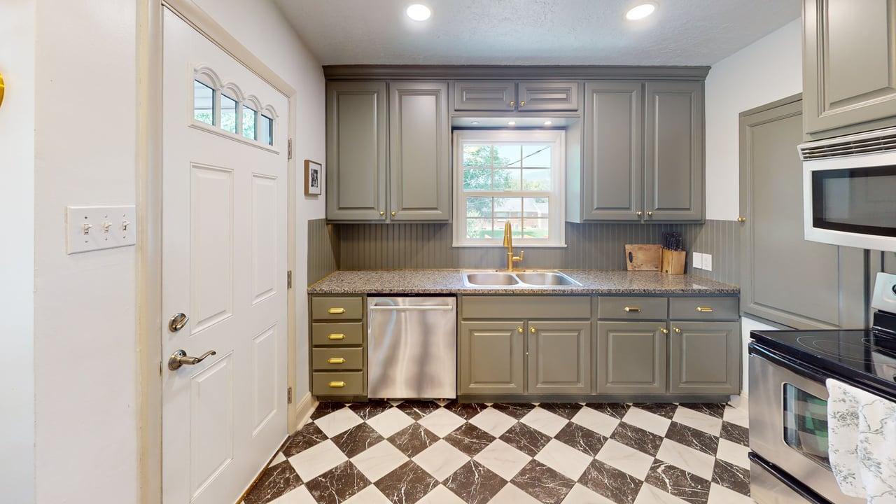 Kitchen featuring checkered flooring, gray cabinetry, stainless steel dishwasher, gold-toned faucet, and recessed lighting