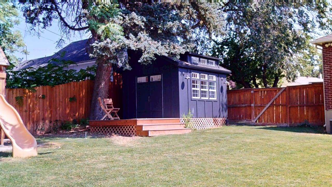 Private fenced backyard featuring a detached storage shed with a wooden deck and double entry doors