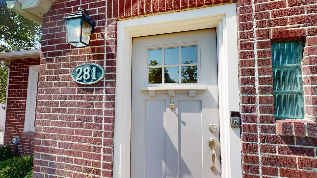 Brick exterior featuring a light-colored entry door with window panes and a transom detail