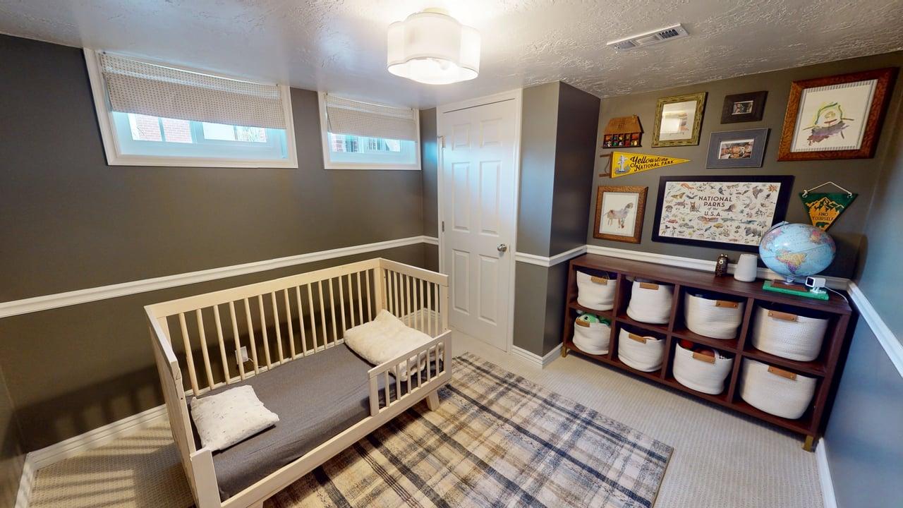 Finished room featuring two horizontal windows with blinds, a built-in storage unit with nine cubbies, dark wall paneling, and a flush-mount ceiling light