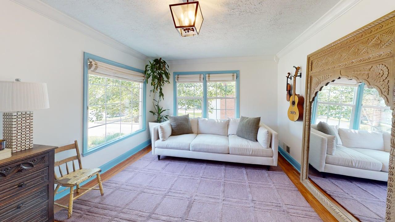 Room featuring multiple windows with blue trim, hardwood flooring, and a decorative ceiling light fixture