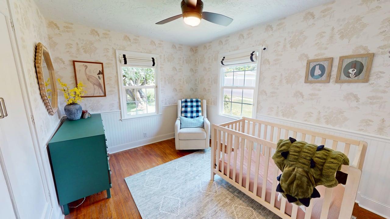 Room featuring wood-finish flooring, white beadboard wainscoting, and patterned wallpaper