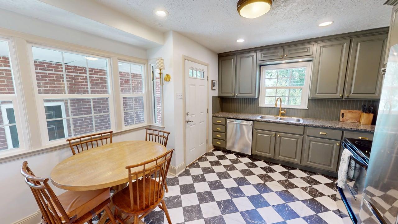 Kitchen featuring checkered tile flooring, gray cabinetry, and a built-in eating nook with bay windows