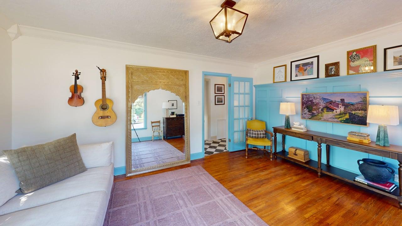Hardwood flooring throughout a spacious room featuring crown molding and a large decorative mirror