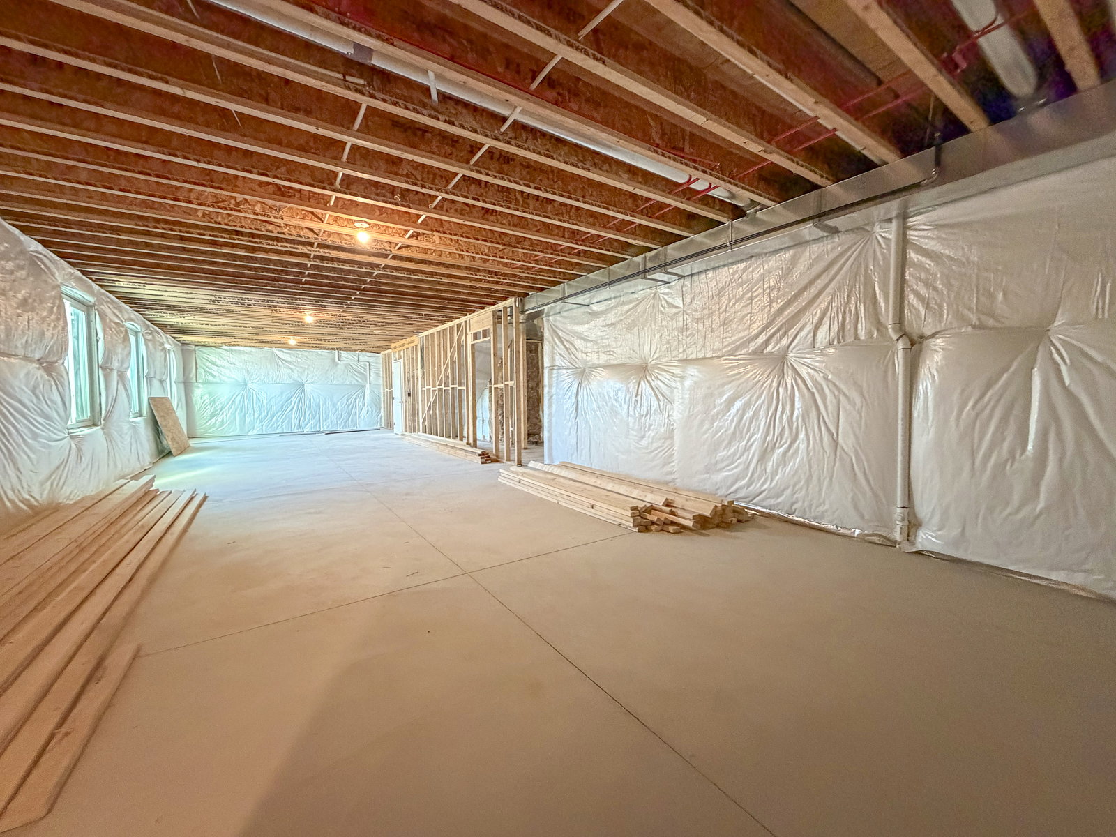 Expansive unfinished basement featuring an open floor plan, exposed wood joists, and concrete flooring