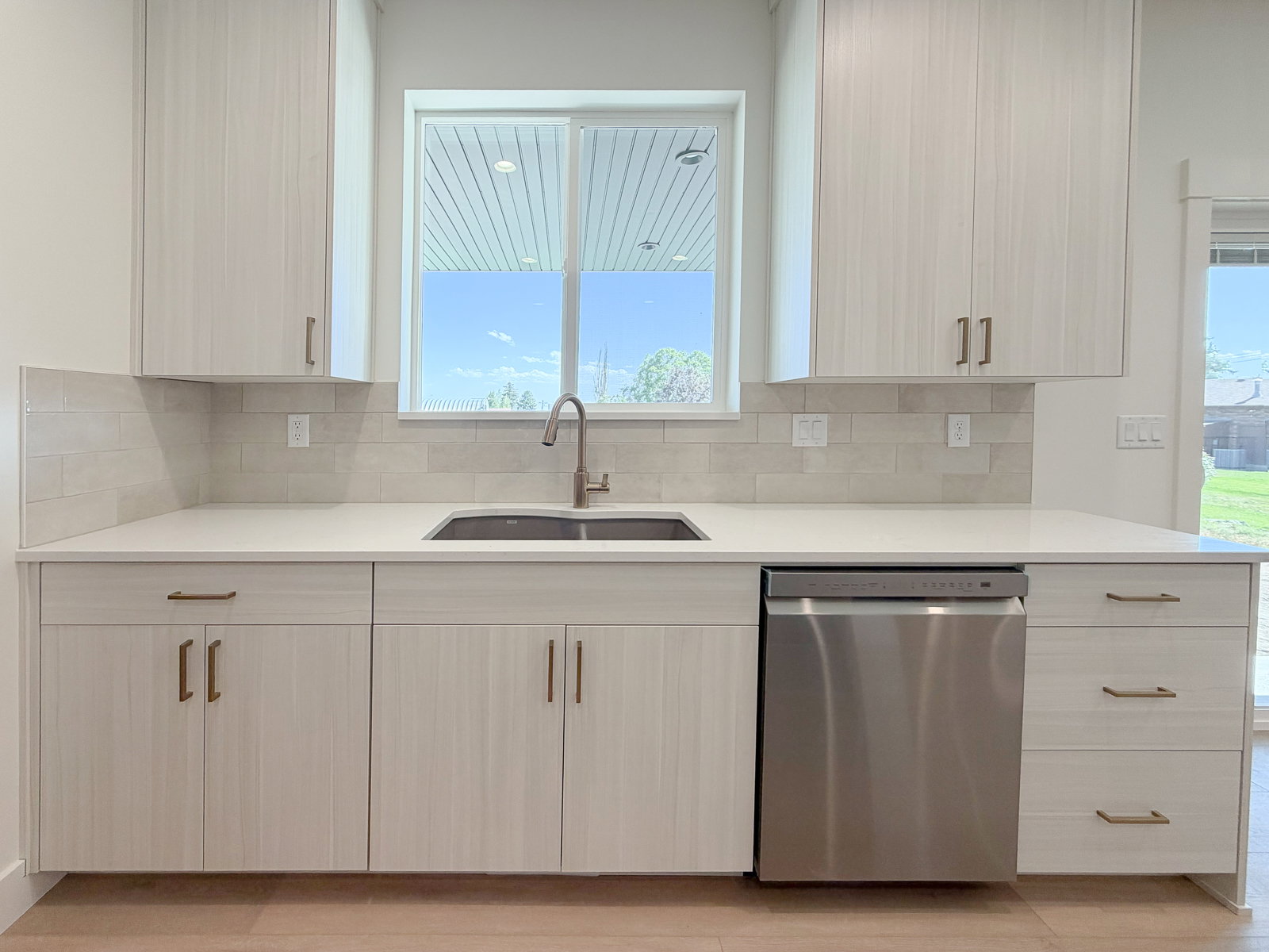 Kitchen featuring wood-finish cabinetry with bronze hardware, a stainless-steel undermount sink, and a stainless steel dishwasher