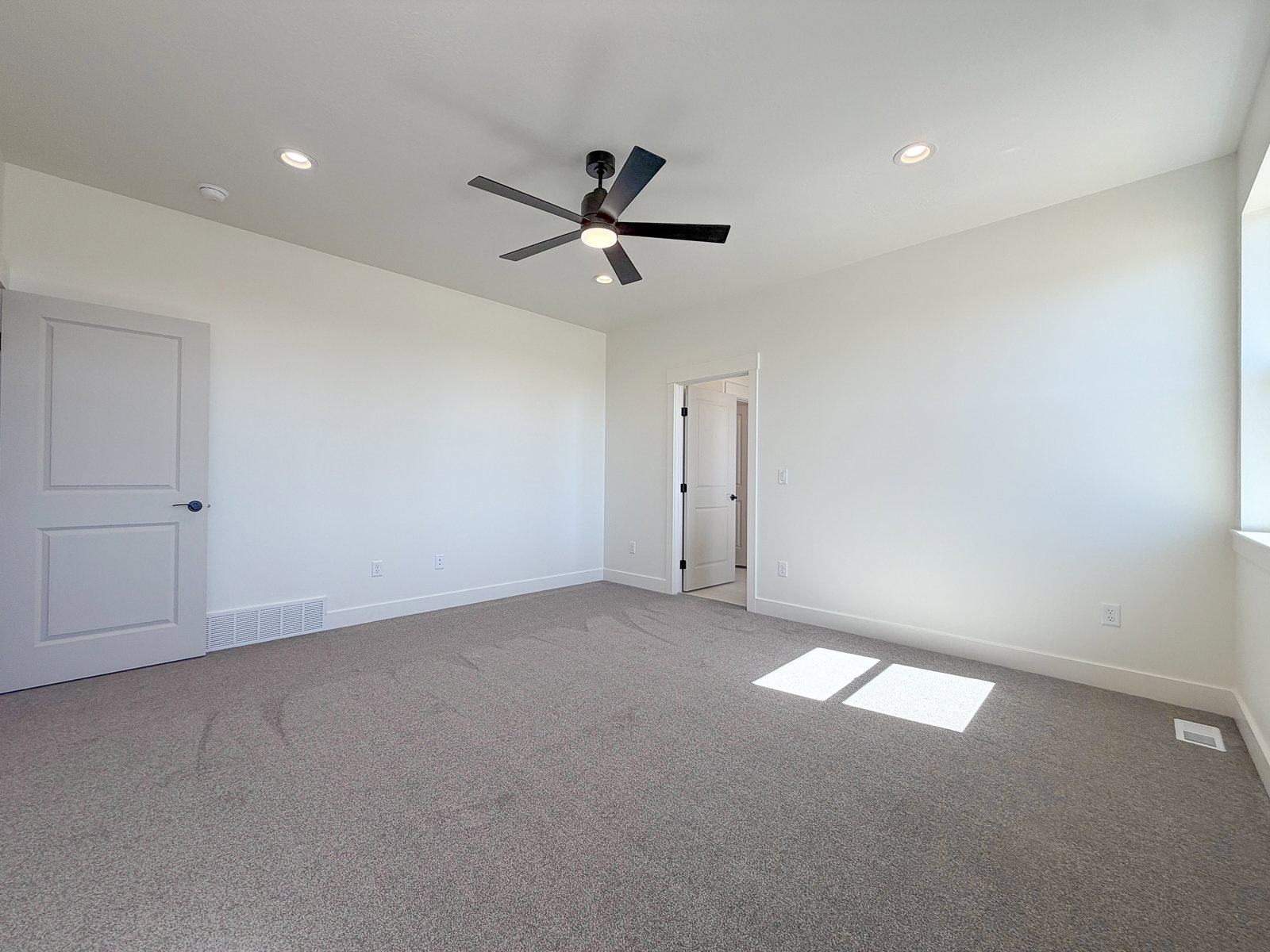 Carpeted interior space featuring a ceiling fan with integrated lighting, recessed ceiling lights, and white trim