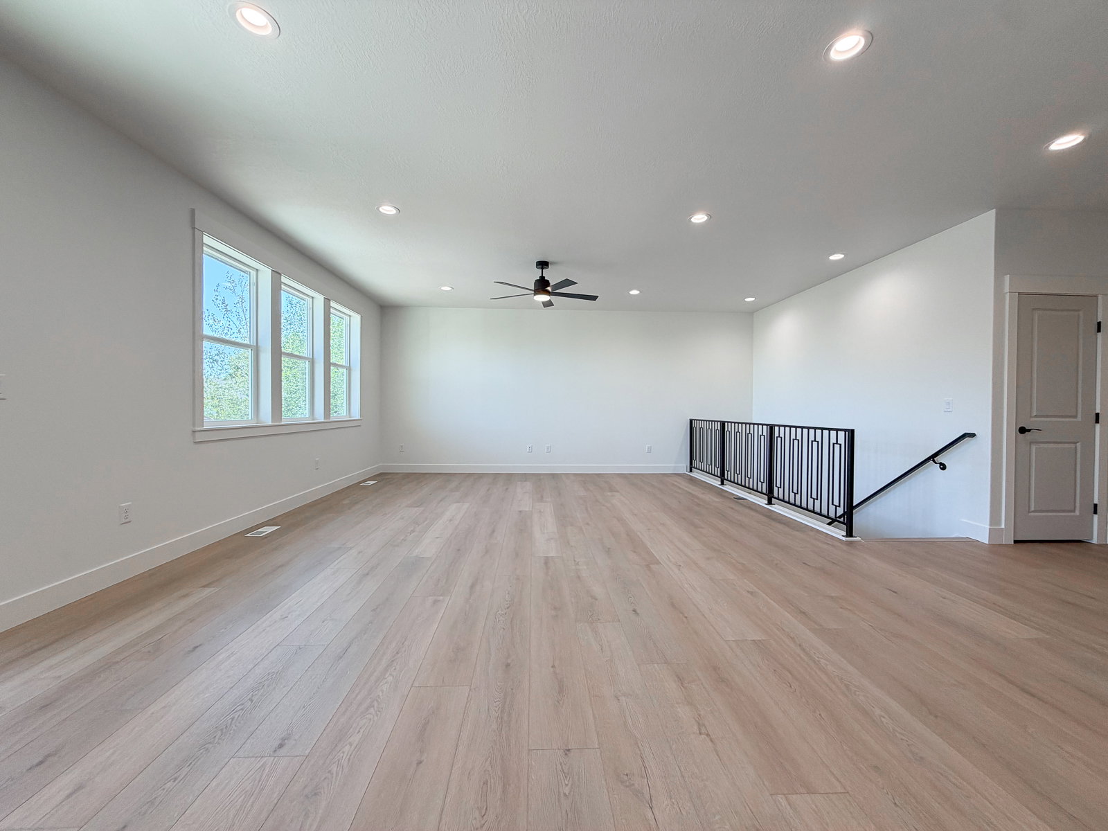 Spacious room featuring light wood-finish flooring, recessed lighting, and a modern ceiling fan