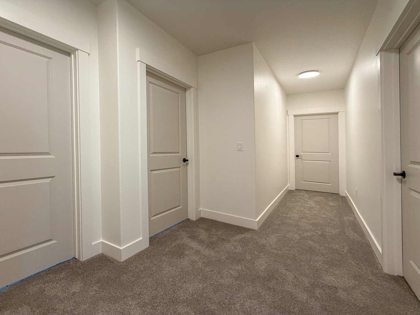 Hallway featuring neutral-toned carpeting, white baseboards, and bright white walls