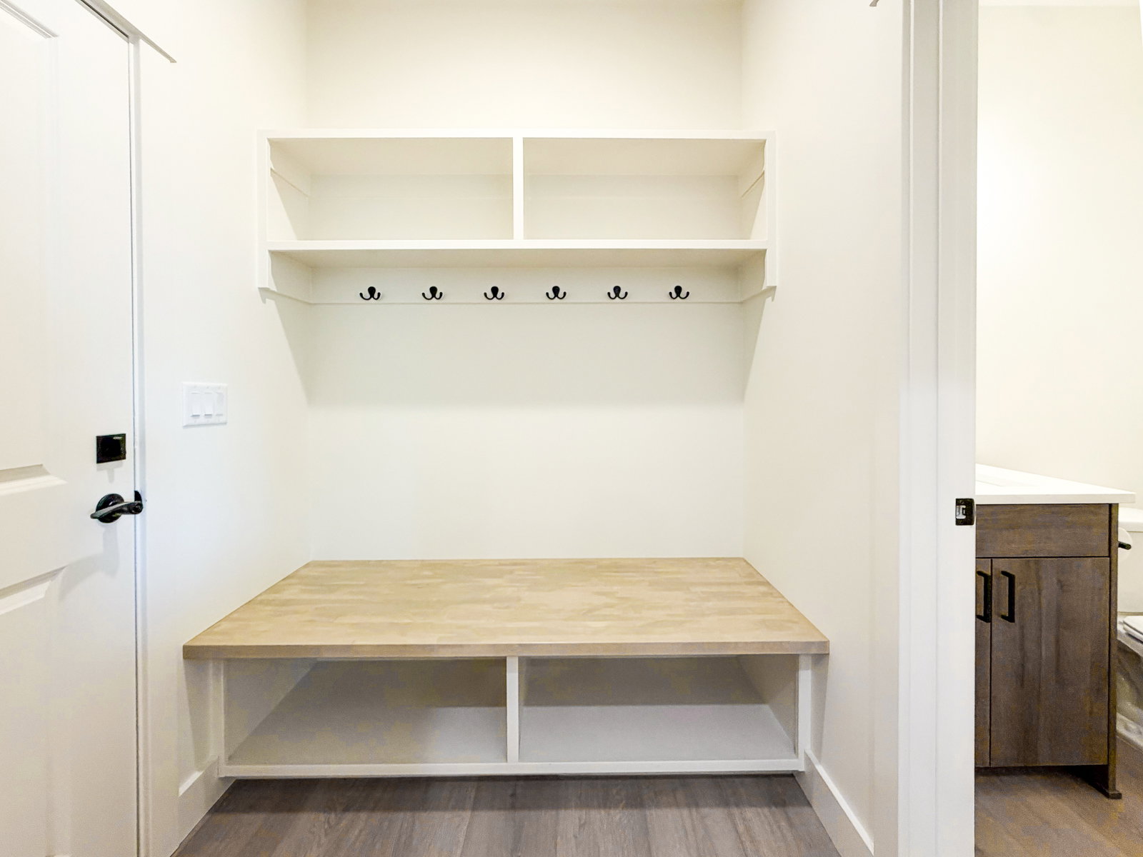 Built-in mudroom bench with natural wood-finish top and open shelving